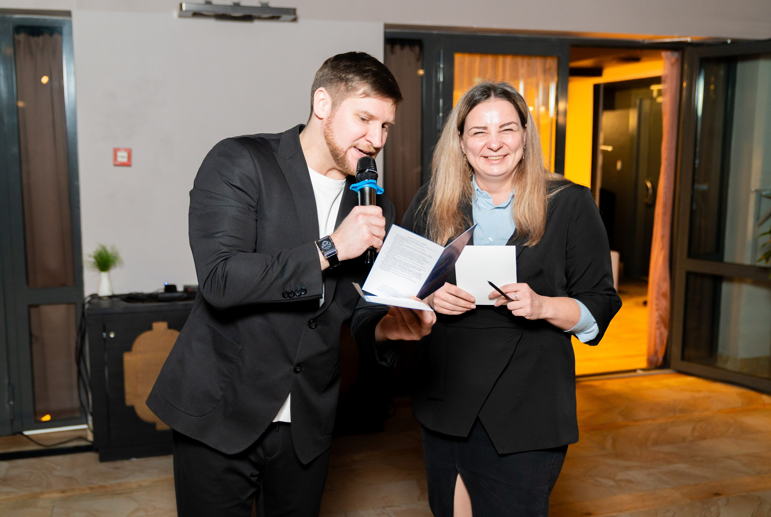 Ведущий и девушка с документами и микрофоном на сцене корпоративного мероприятия Radisson Sonya. Фотограф Евгений Мальцев