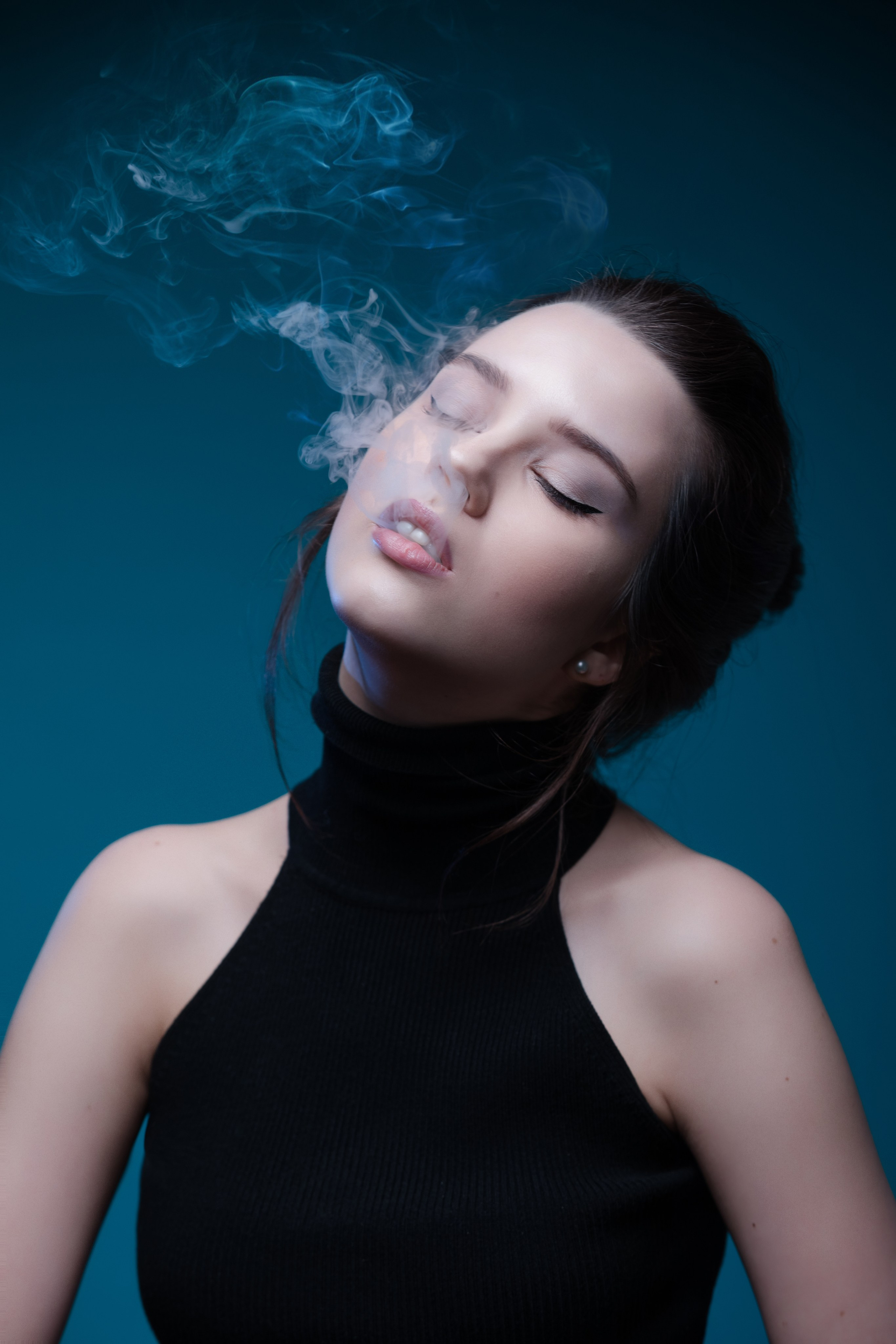 Красивая бледная девушка выпускает дым изо рта