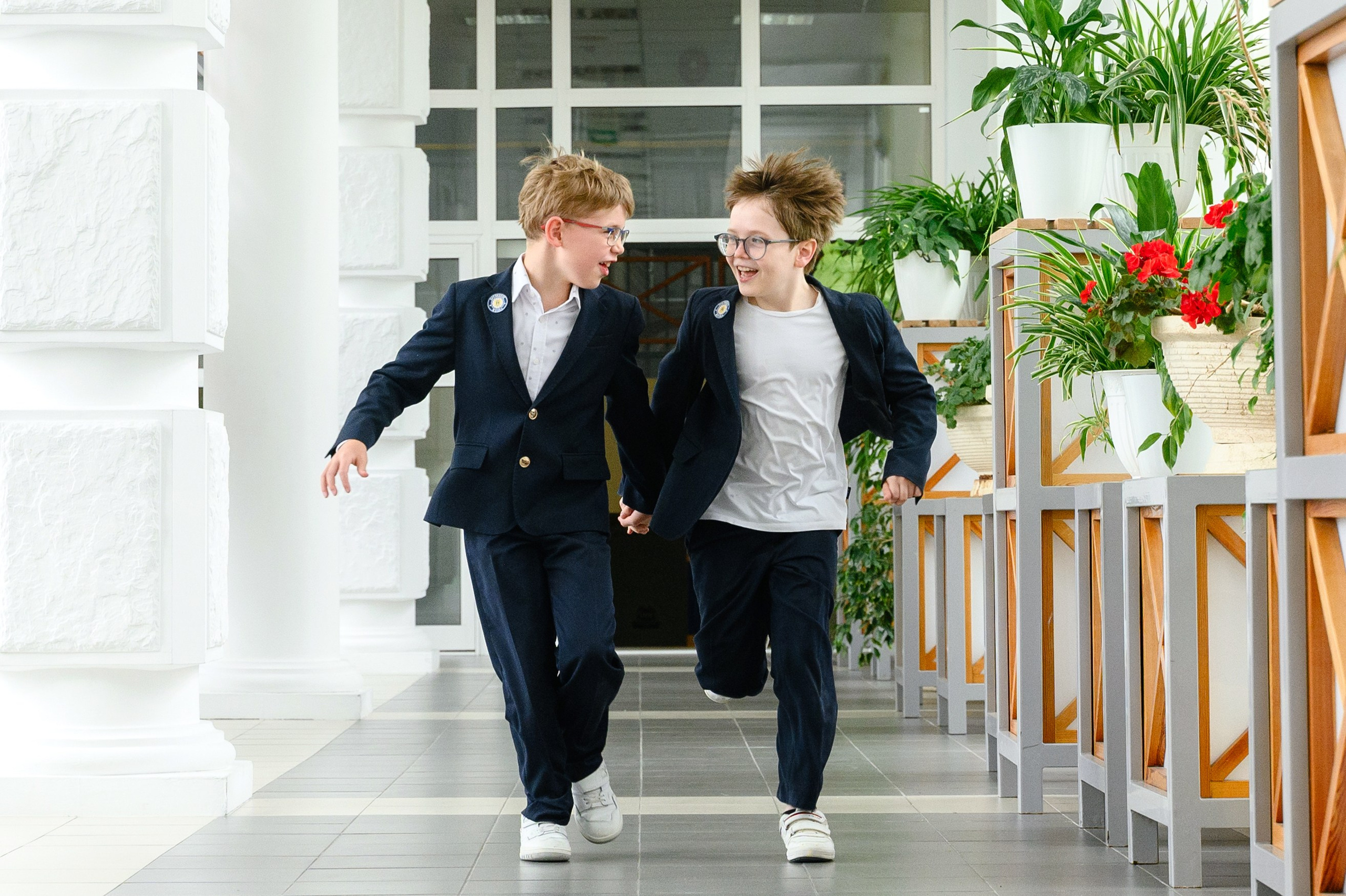 Два школьника бегут по коридору, держась за руки