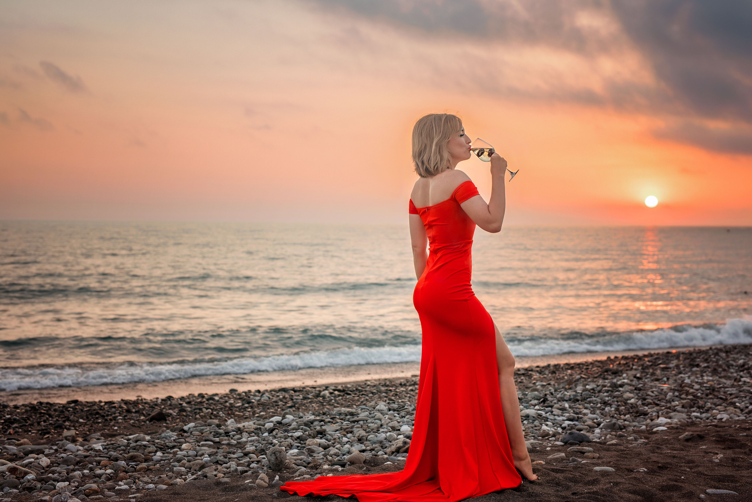 Девушка пьет вино на закате на пляже Мандарин в Адлере