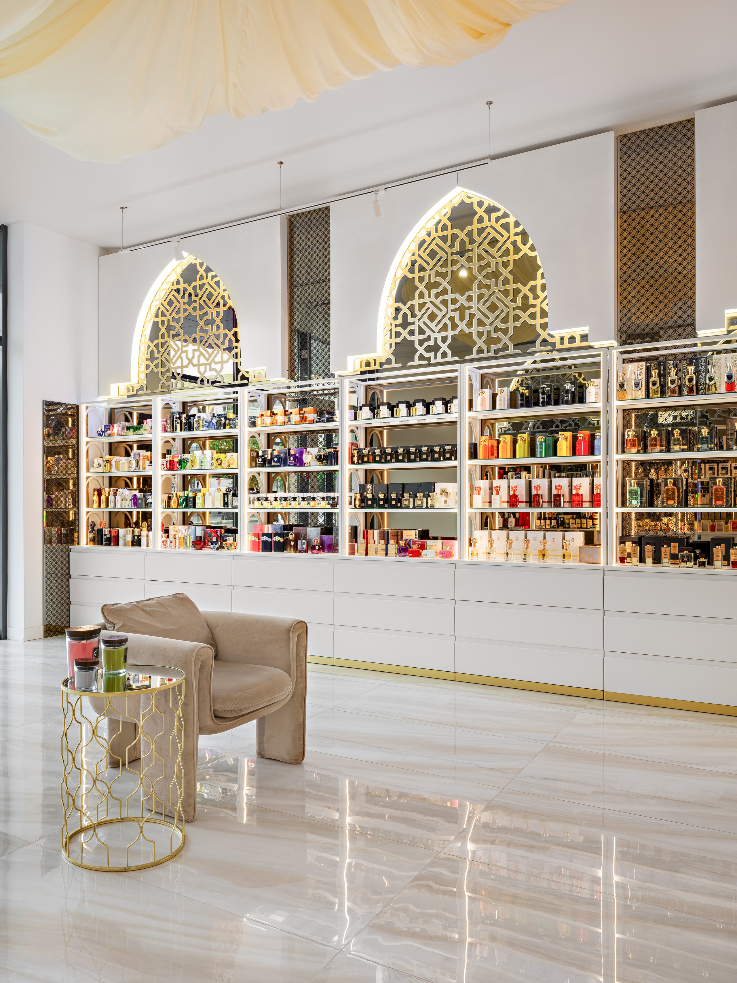 Парфюмерный бутик с восточными арками, зеркальными вставками, белыми витринами и коллекцией элитных ароматов. Интерьер с мраморным полом и мягким креслом, дизайнер Мария Никишина, фотограф Сергей Денисенко.