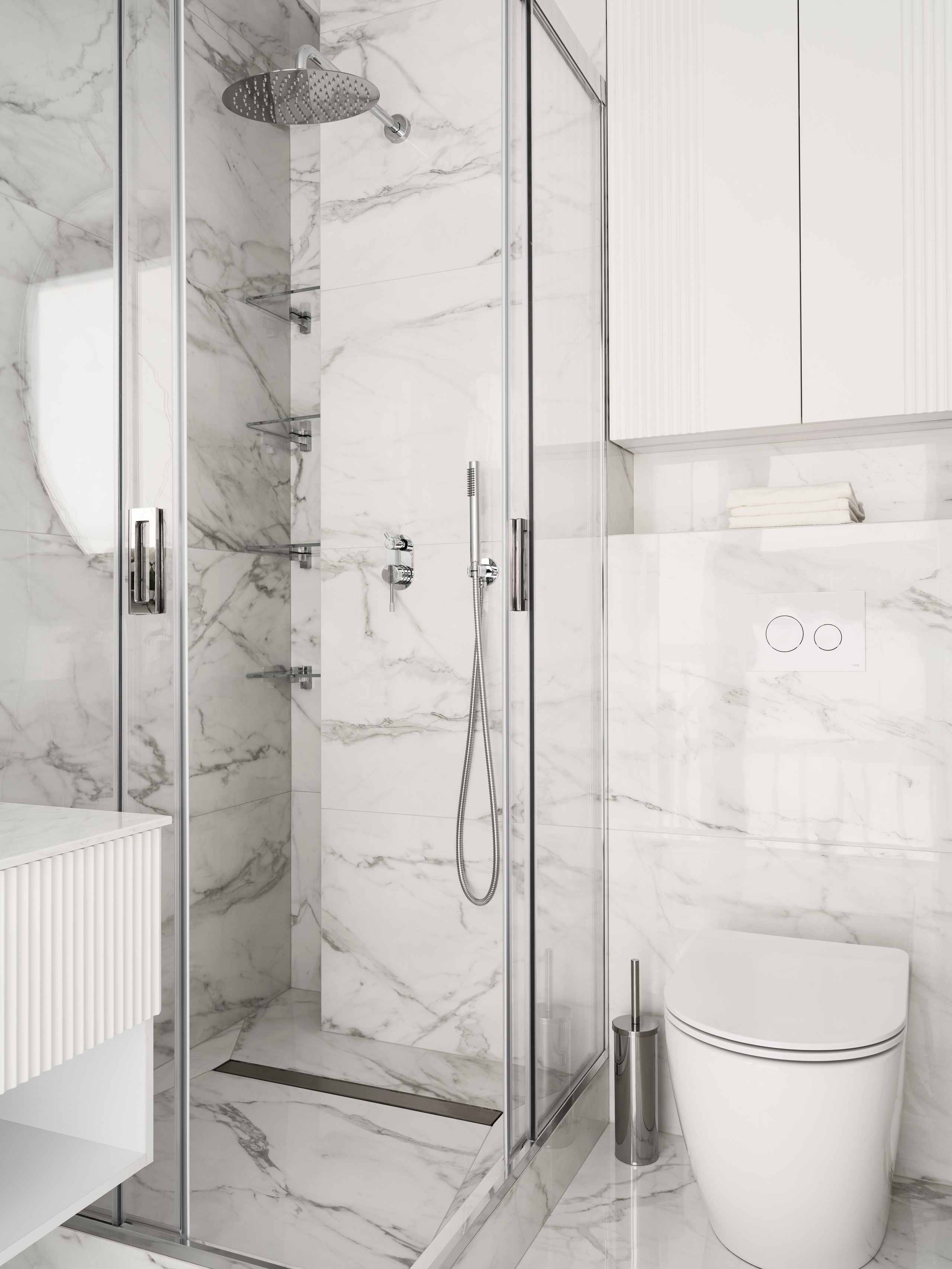 Современная душевая зона с прозрачной стеклянной кабиной, мраморной отделкой стен и встроенным верхним душем — лаконичный и функциональный дизайн ванной от Алёны Боярской, стилист Наталья Якушева, фотограф Сергей Денисенко.