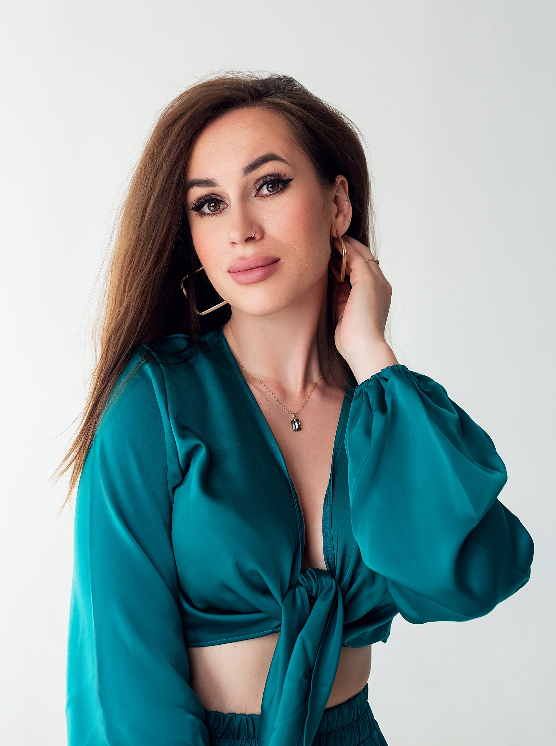 Красивая девушка в изумрудном костюме пижамного стиля, фотоссесия на циклораме в студии.