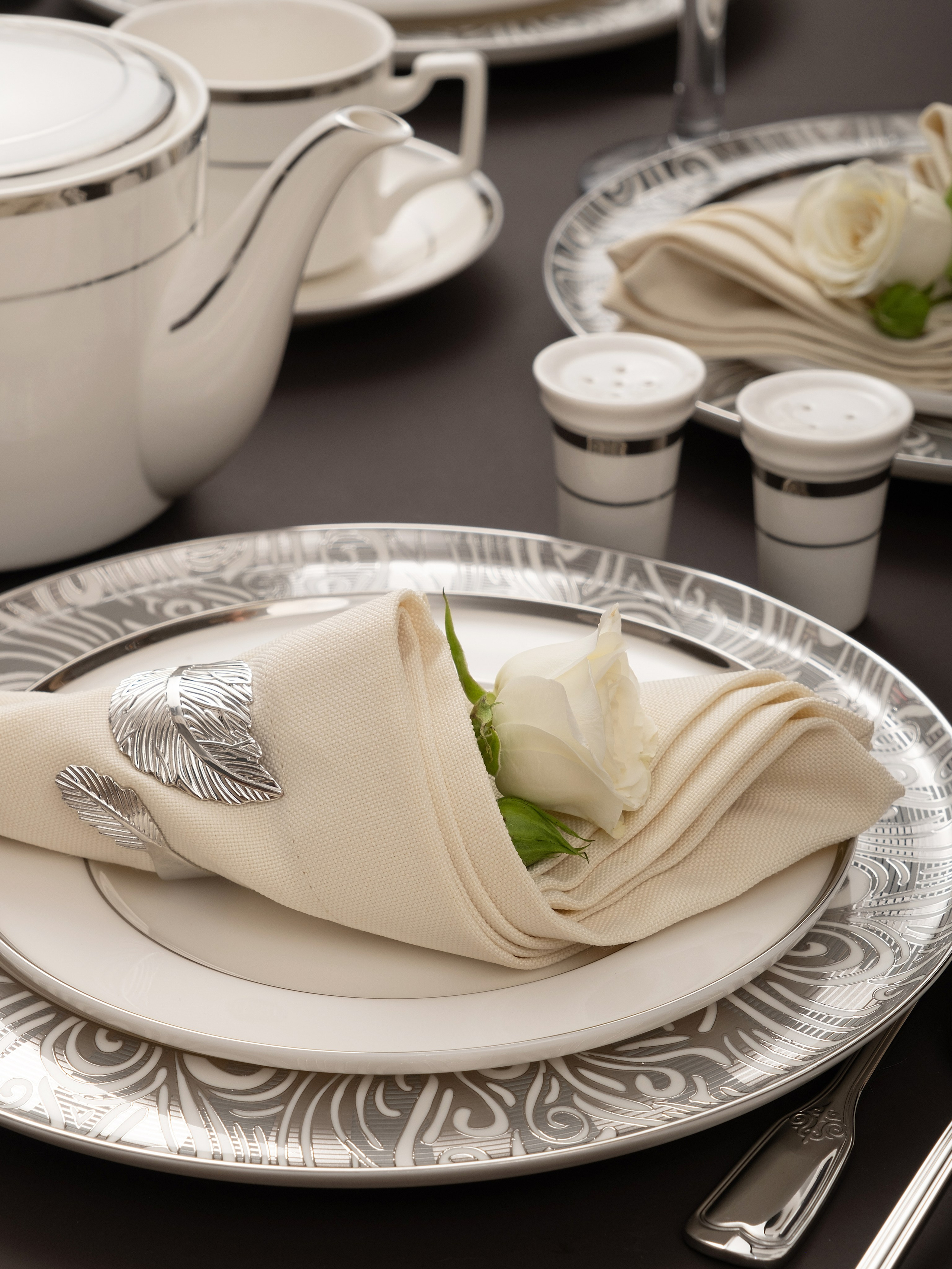 Белая посуда WASEELA и сложенная салфетка в сервировке стола.
