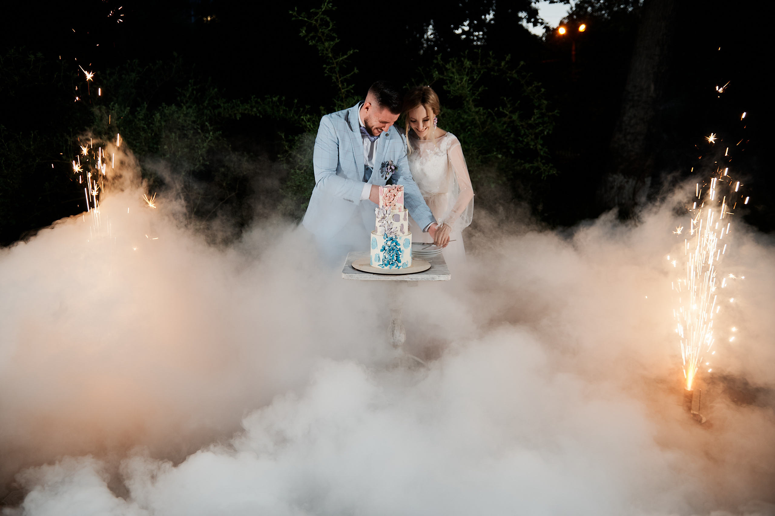 жених и невеста разрезают свадебный торт  украшенный бабочками 