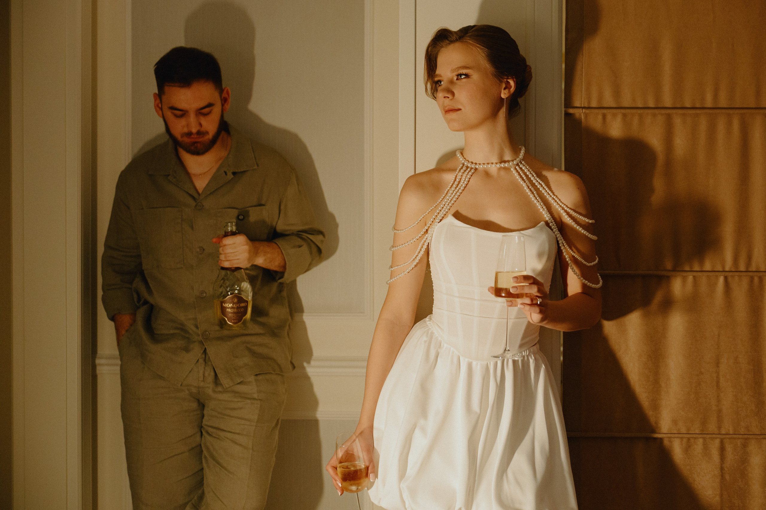 Жених и невеста стоят у дверного проема, держа в руках бокалы.