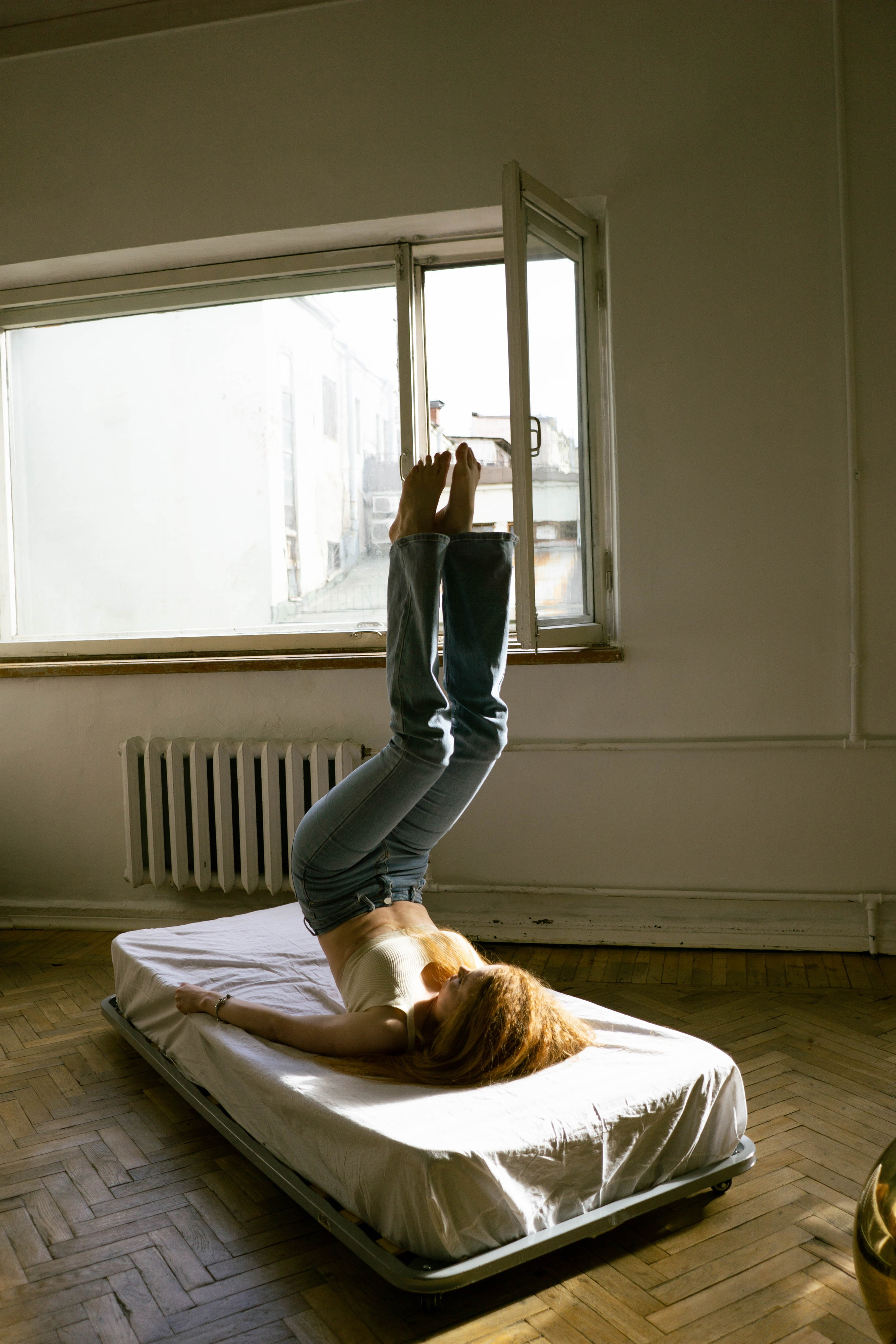 девушка кривляется в студии на матрасе под солнцем 