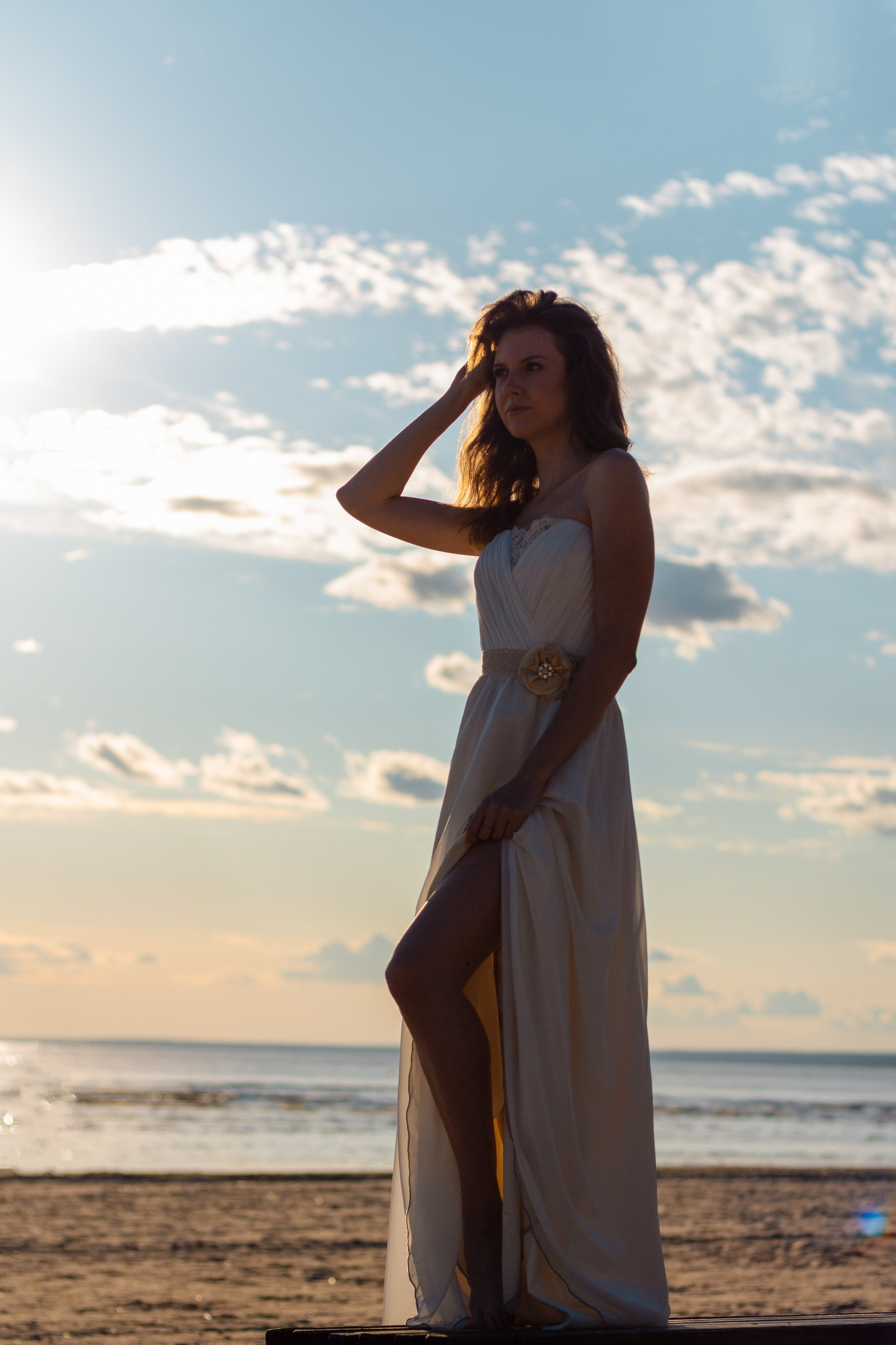 Девушка на берегу залива в песке. Красивая девушка в белом платье.