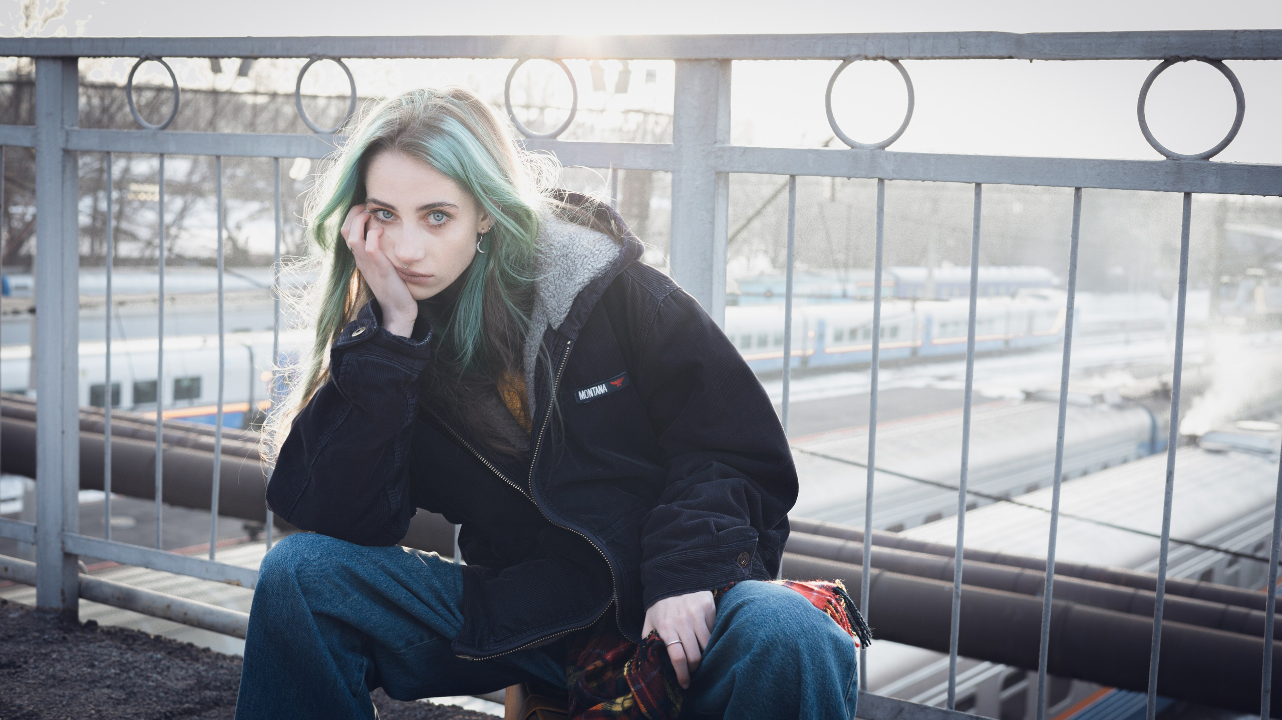 Портрет девушки в чёрной куртке на мосту с перилами
