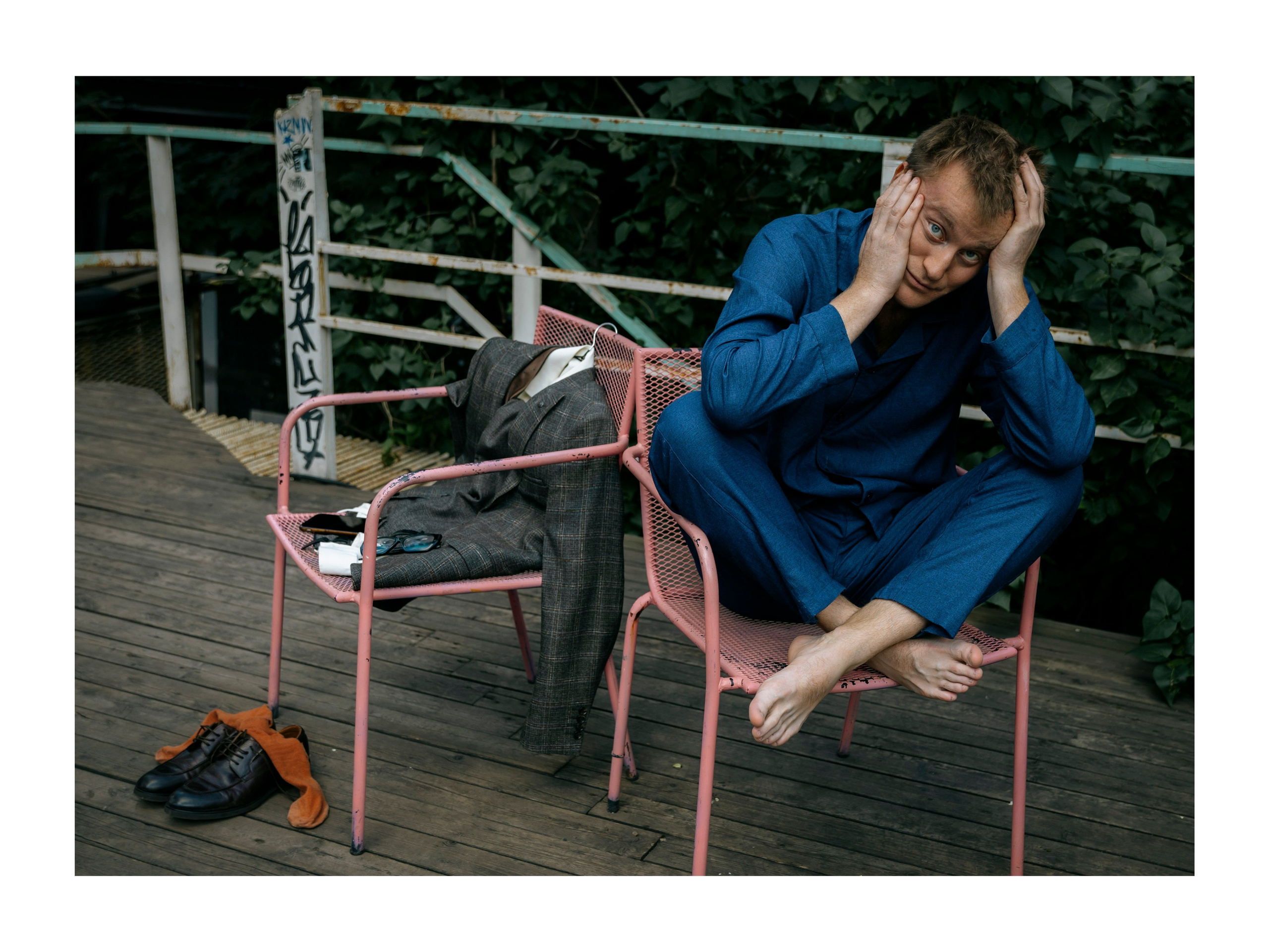 мужчина в синей пижаме сидит на стуле на улице