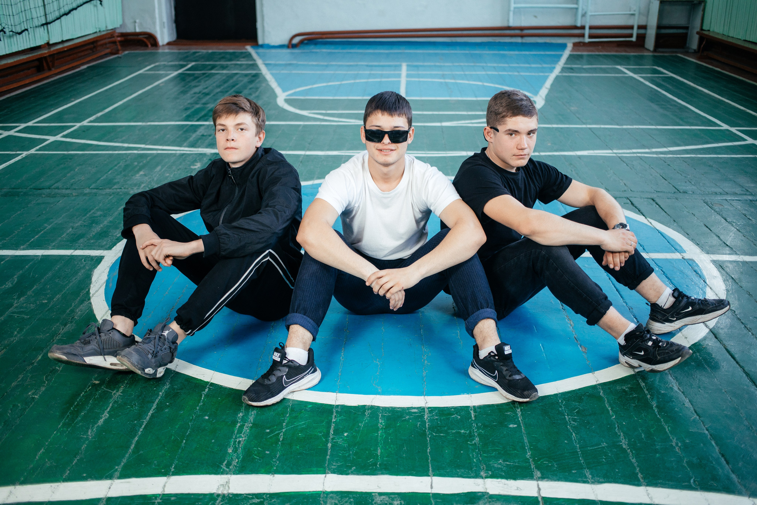 Трое парней 11 класса в спортивном зале позируют для выпускного альбома в Усть-Каменогорске