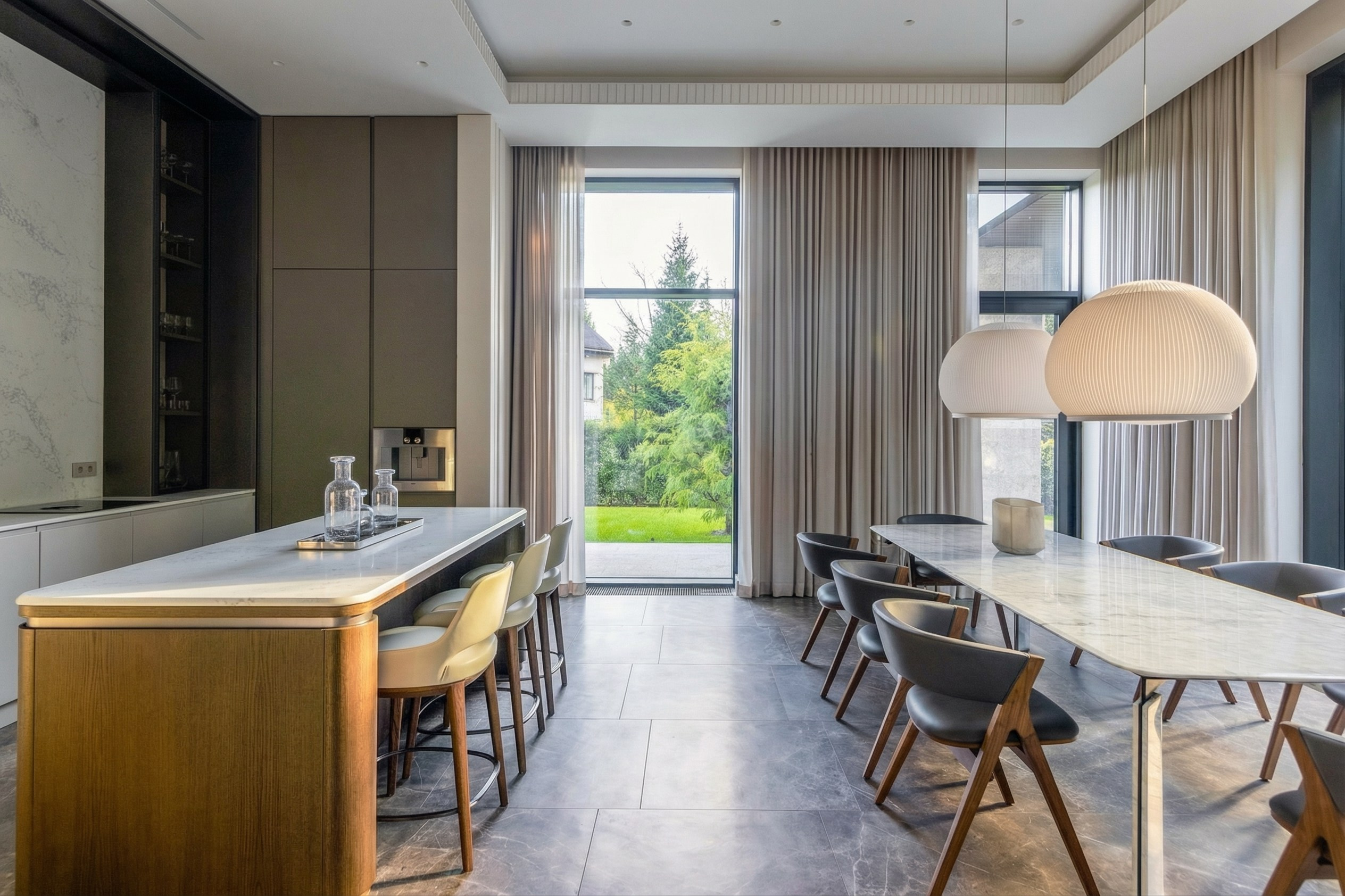 Панорамный вид кухни-столовой с мраморным обеденным столом, кухонным островом из дерева и панорамным остеклением с видом на сад, проект Валерии Котович.