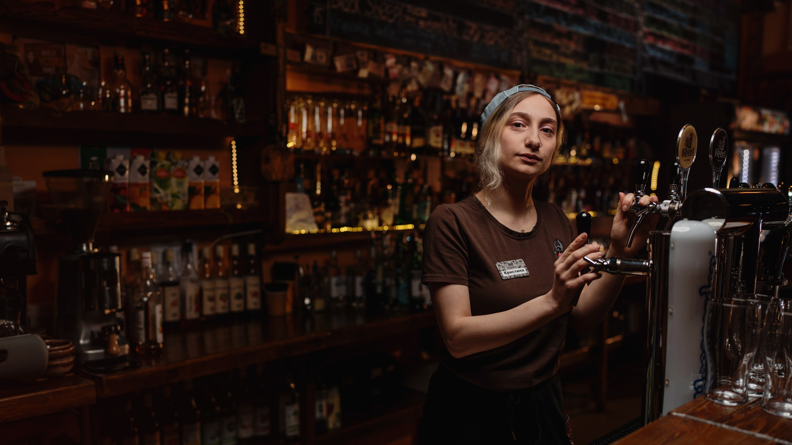 девушка бармен стоит за стойкой