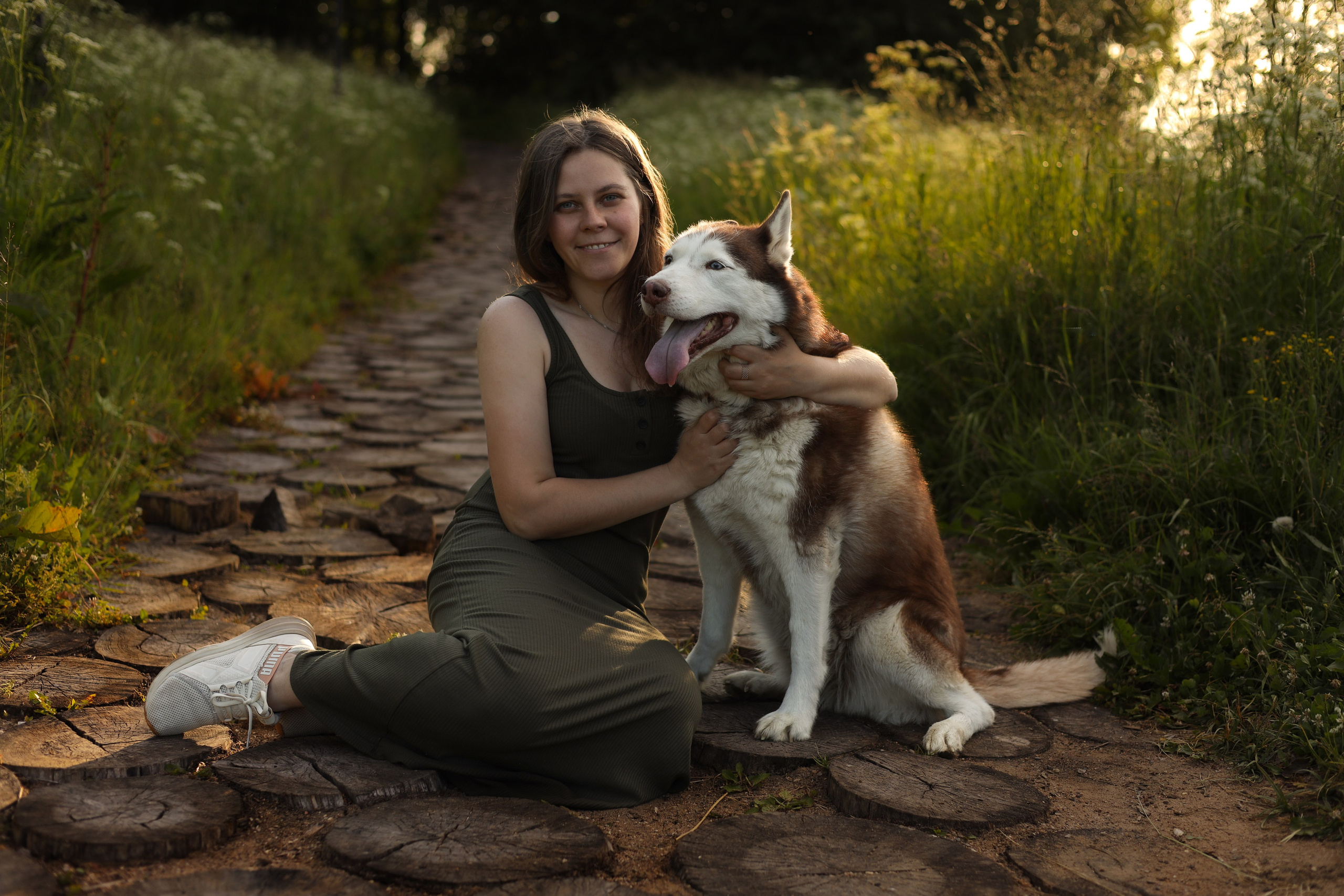 девушка сидит с собакой обнимает ее на фотосессии на природе 