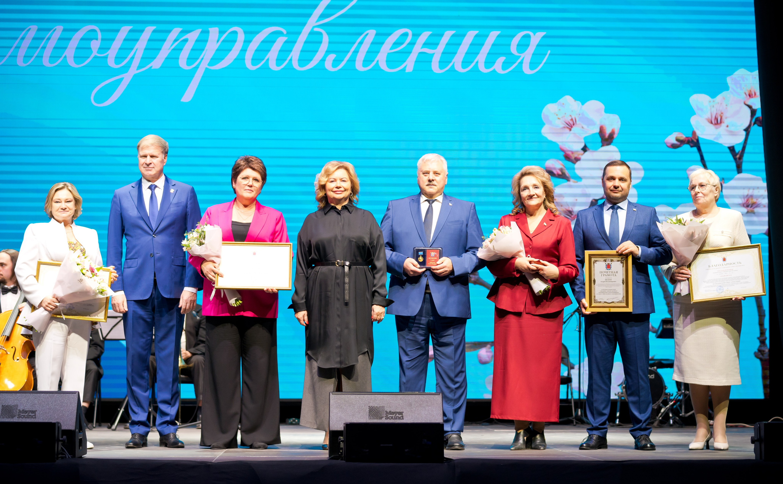 Групповое фото награждённых: участники церемонии с грамотами, медалями и букетами на сцене. День местного самоуправления в Санкт-Петербурге. Фото Евгения Мальцева.