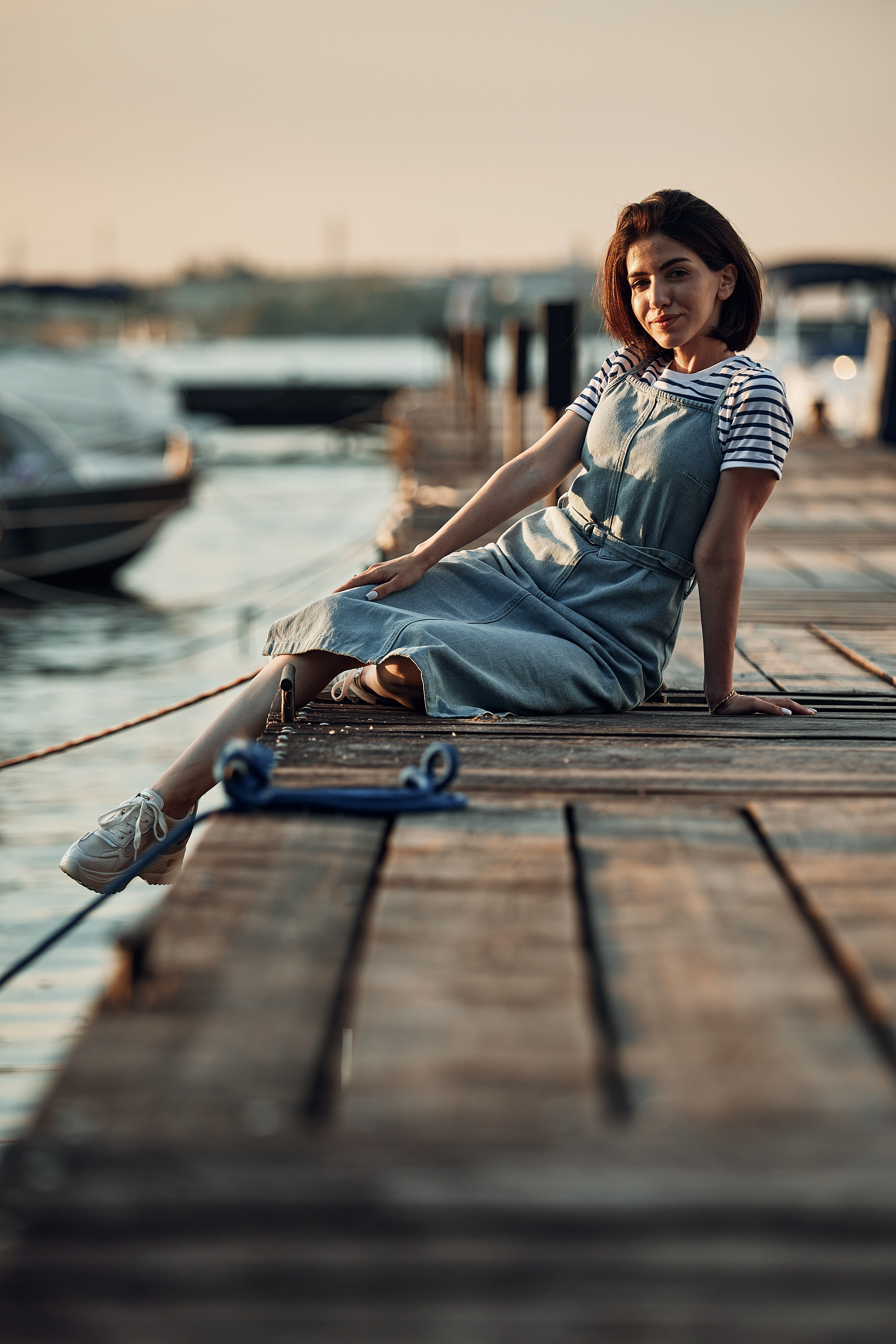 Девушка сидит на пирсе вечером