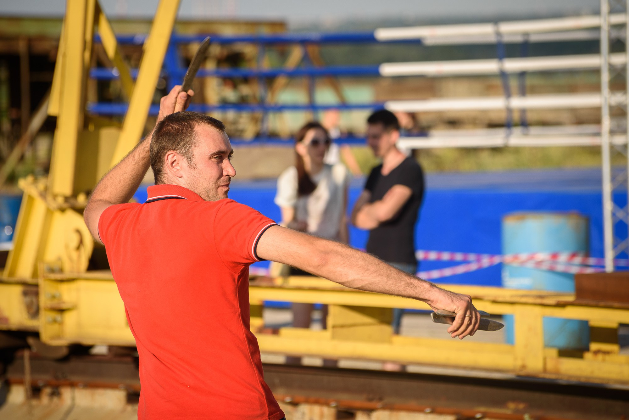 Мужчина в красной футболке готовится к броску ножа в мишень