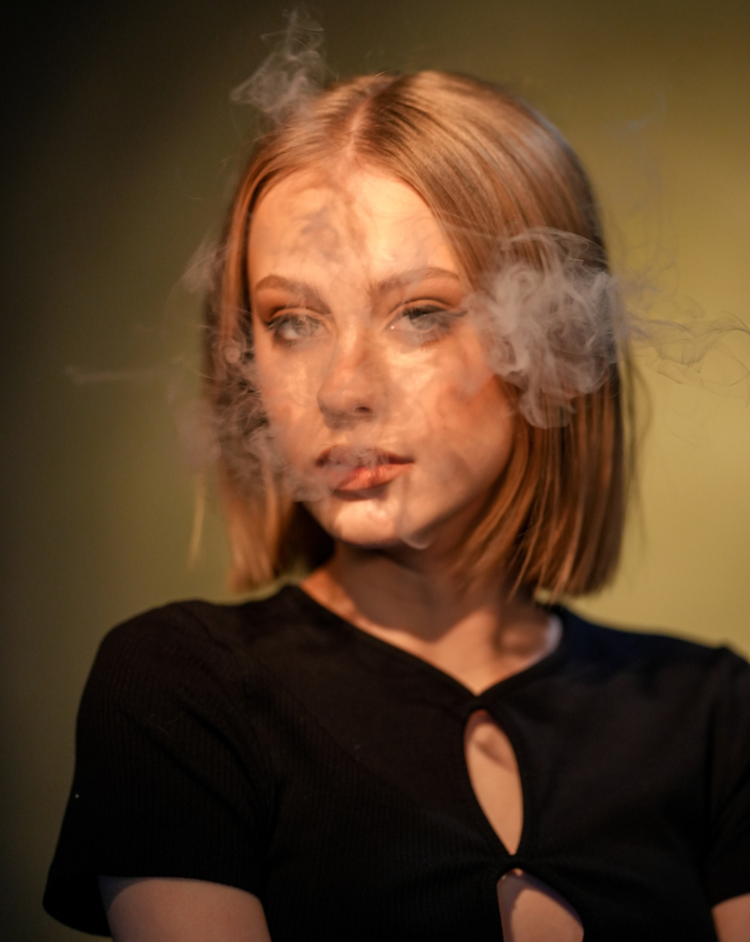 Лицо юной блондинки в дыму.