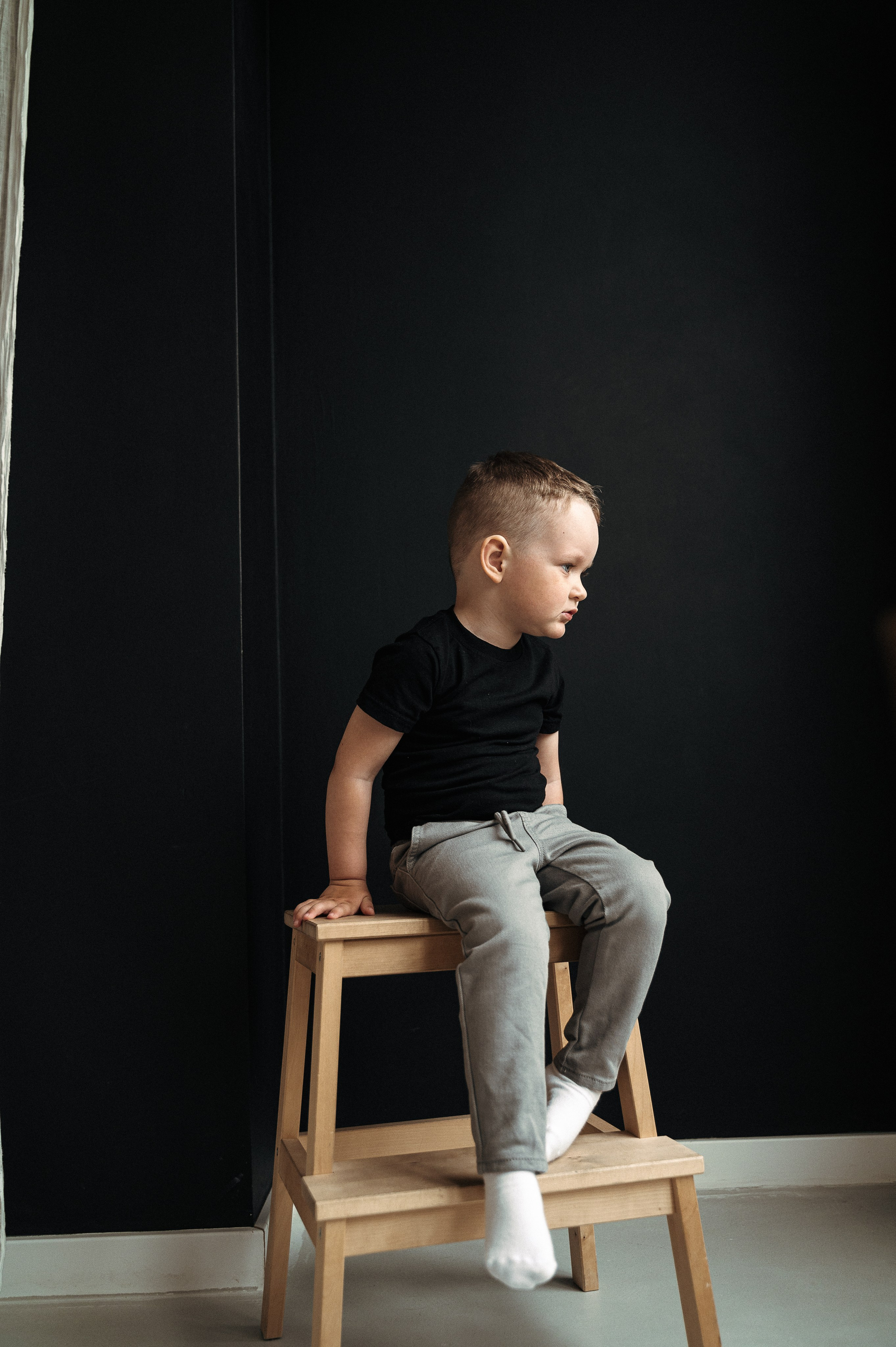 стильный портрет мальчика в черной футболке на черном фоне