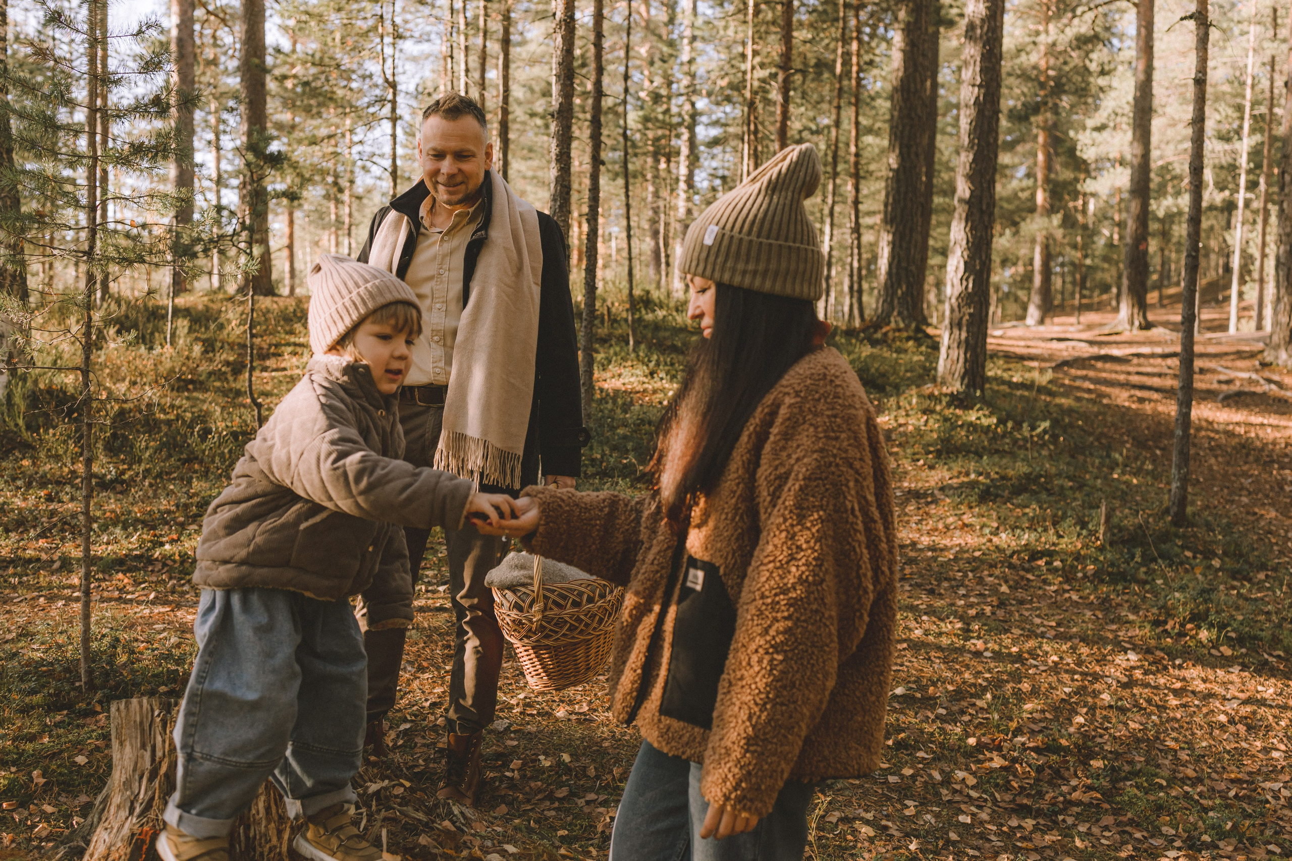 Мелодичная прогулка: мальчишка внимательно рассматривает найденные сокровища под пристальным взглядом родителей