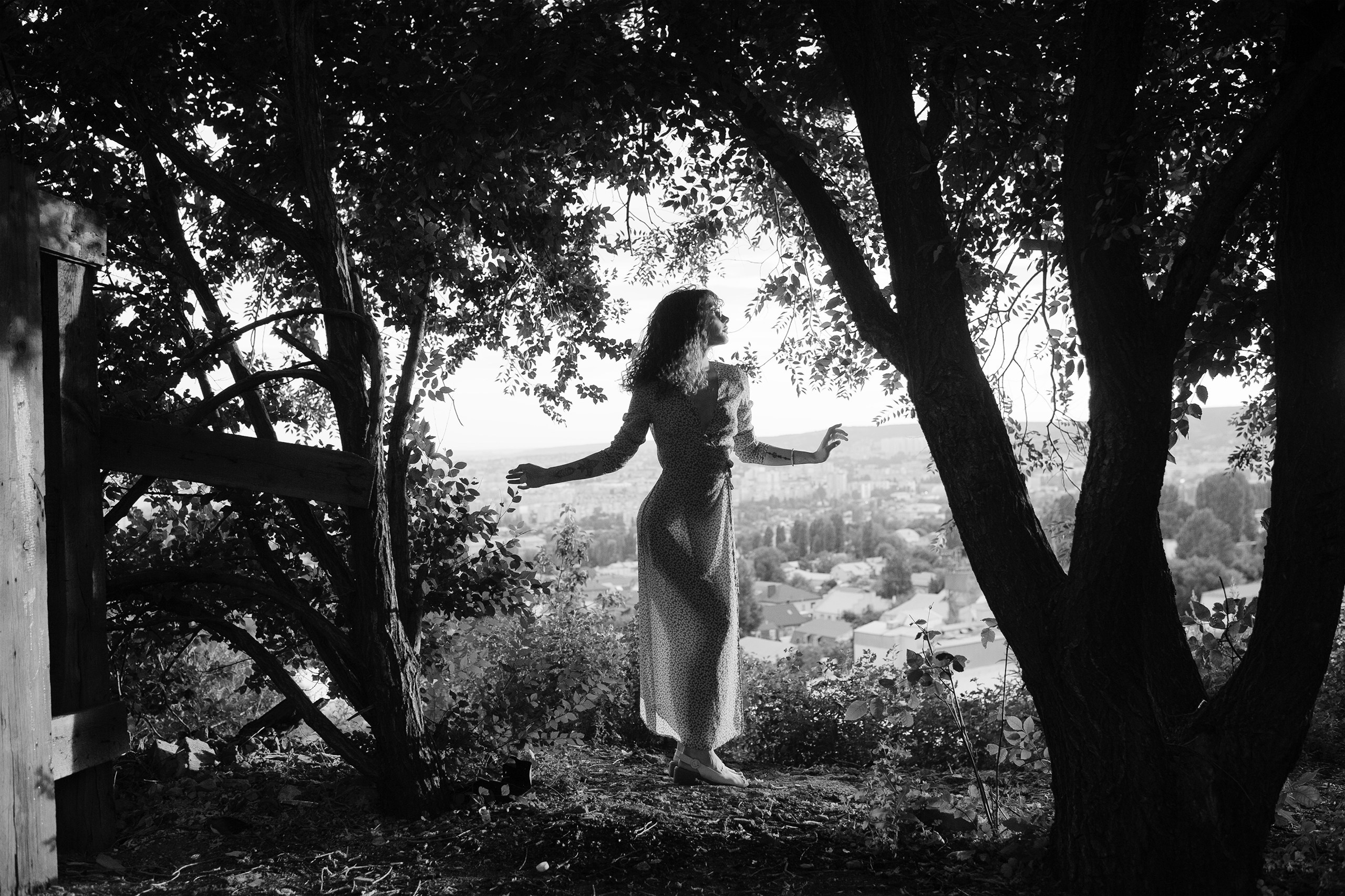 Силуэт танцующей у деревьев девушки в черно-белом цвете