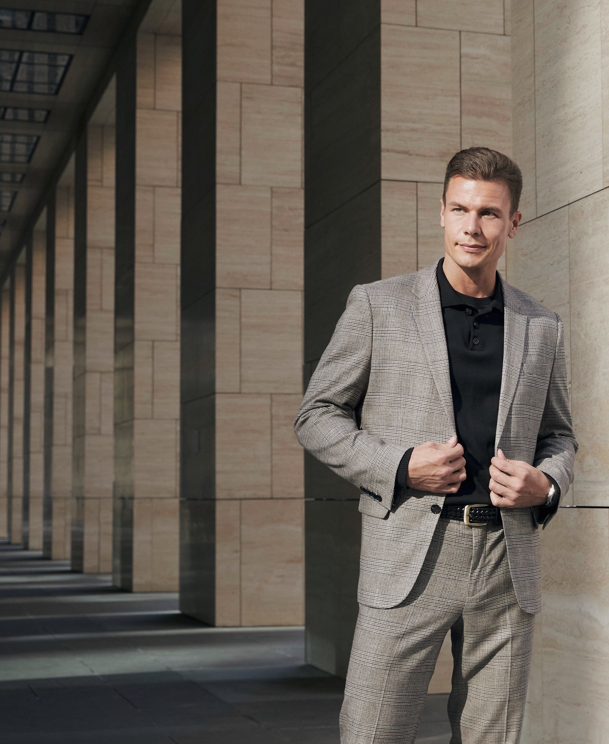 Мужчина модель в сером клетчатом деловом костюме 