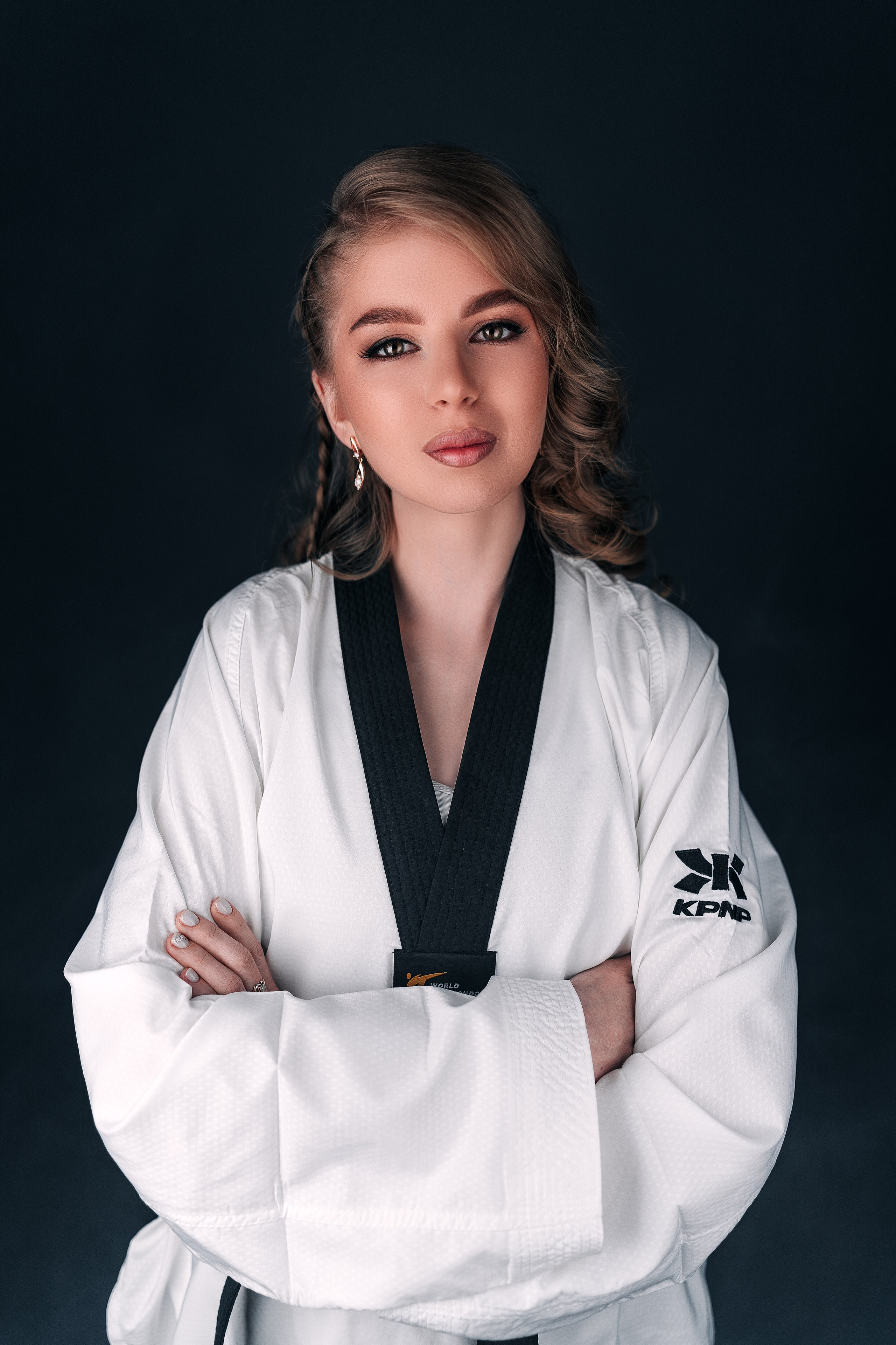 Девушка тхэквондистка, одетая в белое кимоно позирует для фото. 