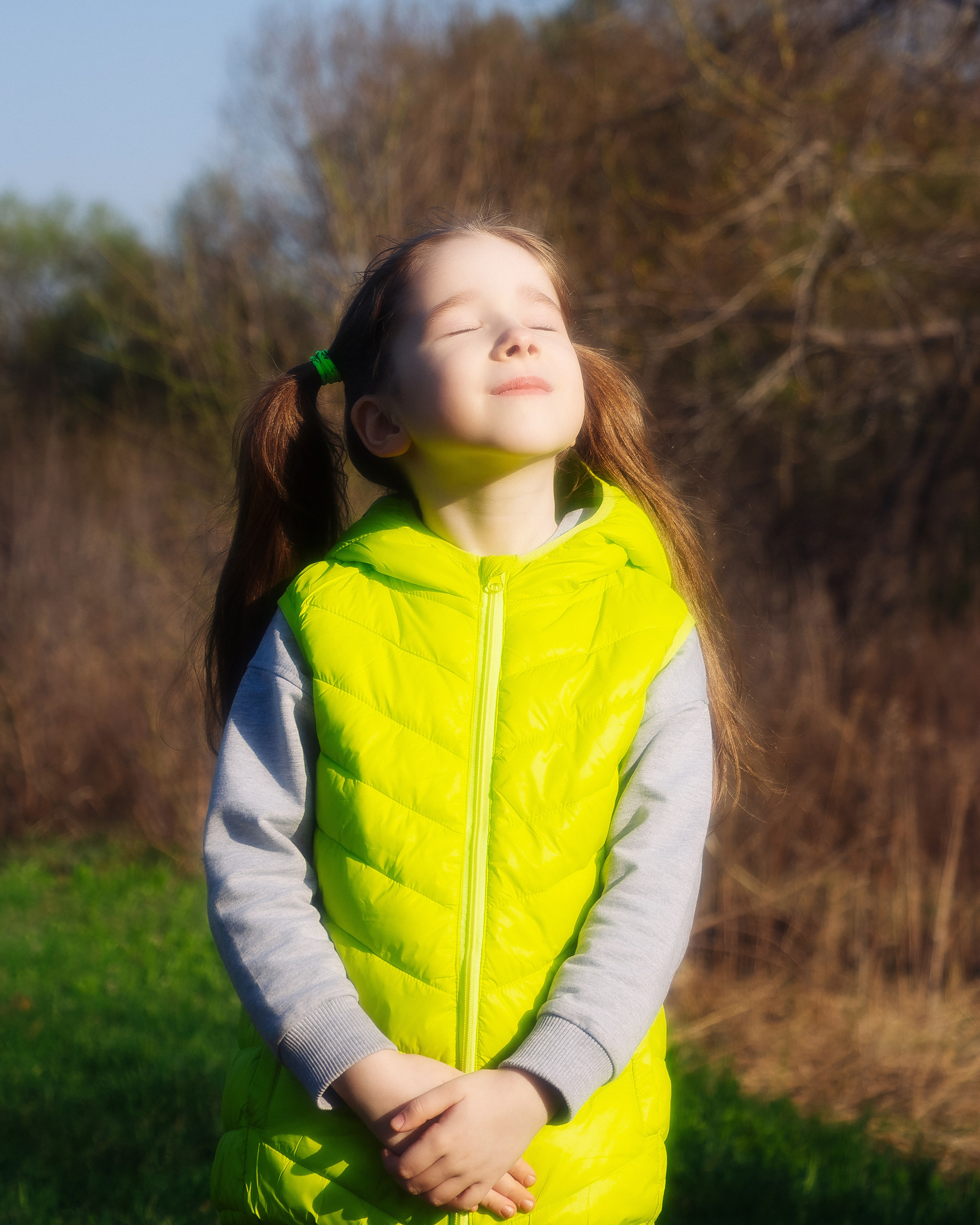 Девочка в зелёной жилетке на улице в солнечную погоду
