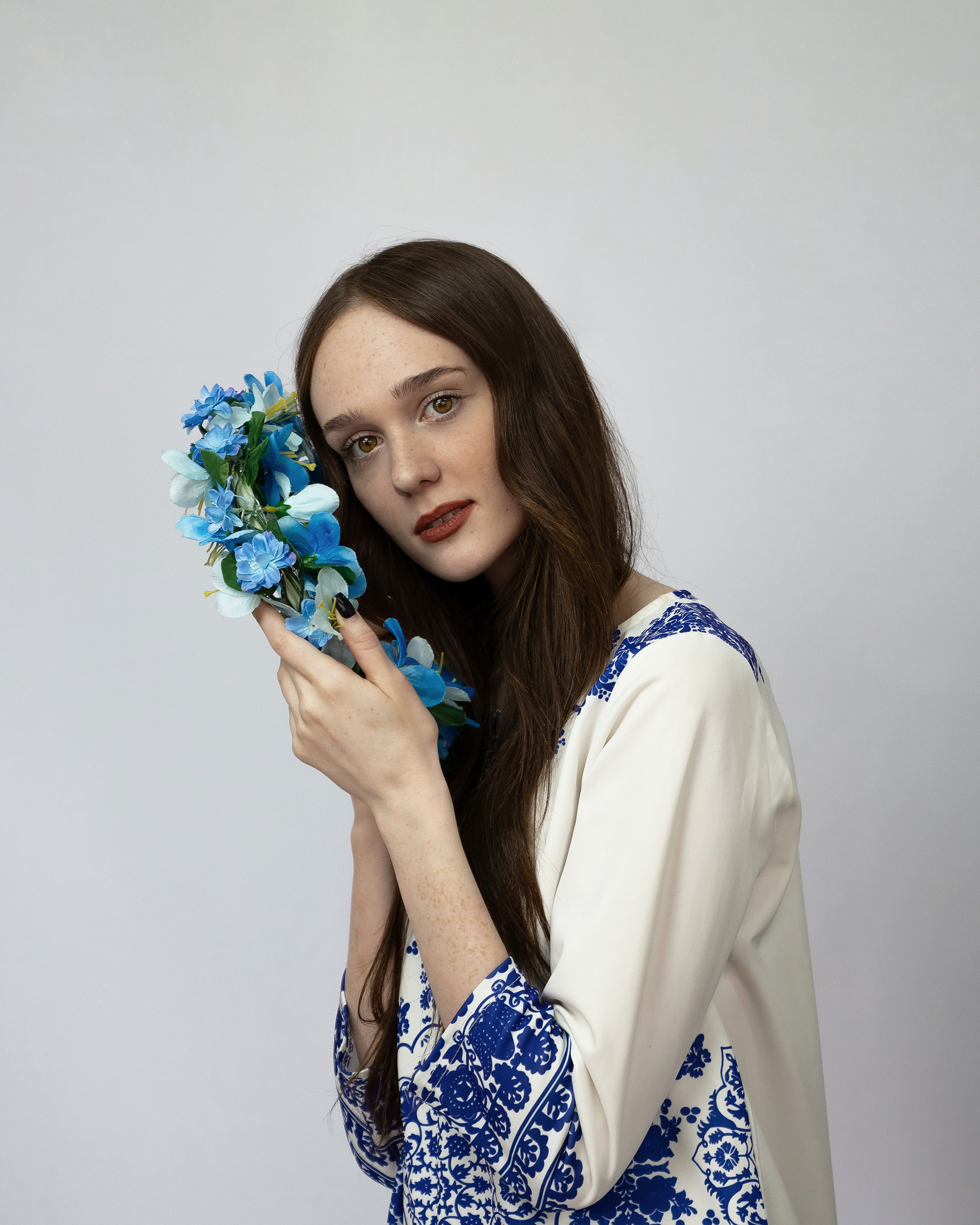 Девушка с веснушками с венком в руках на белом фоне