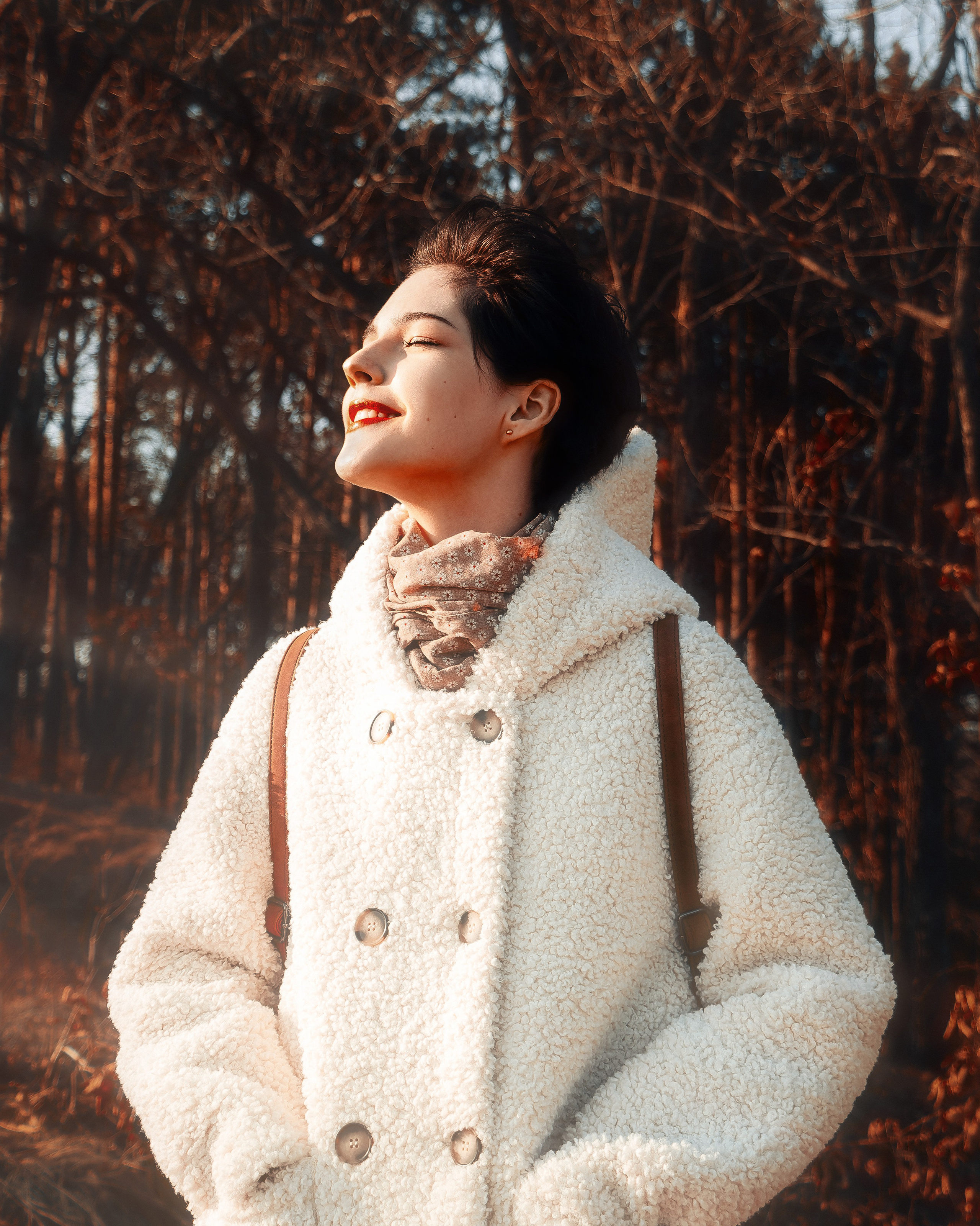 Девушка на улице около ёлок в солнечную погоду