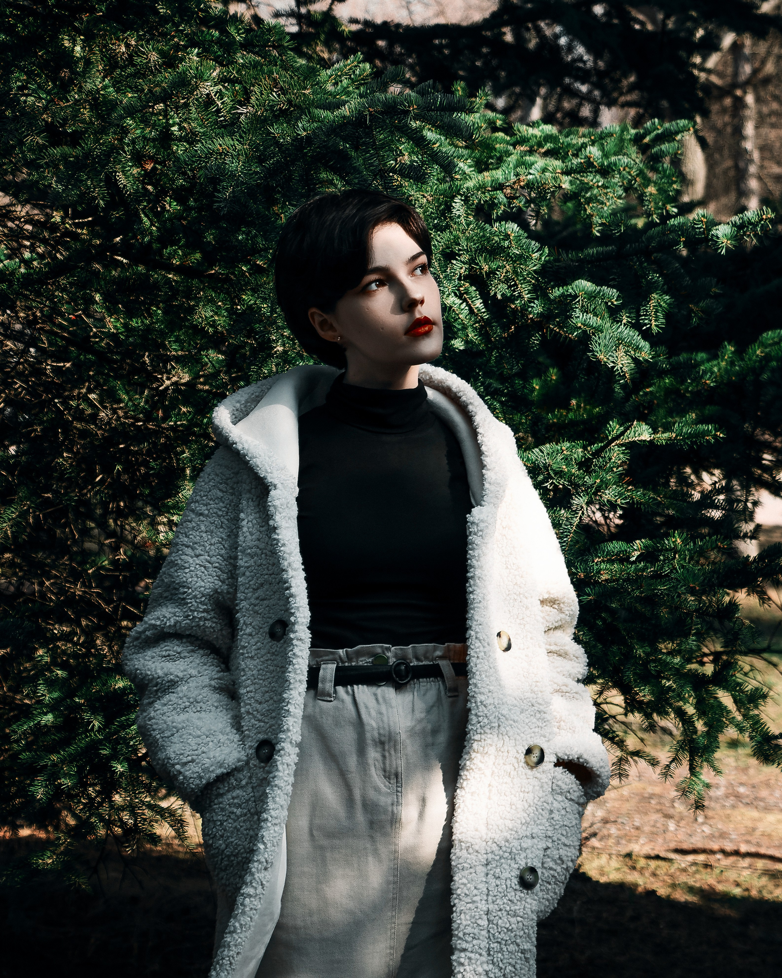 Девушка на улице около ёлок в солнечную погоду