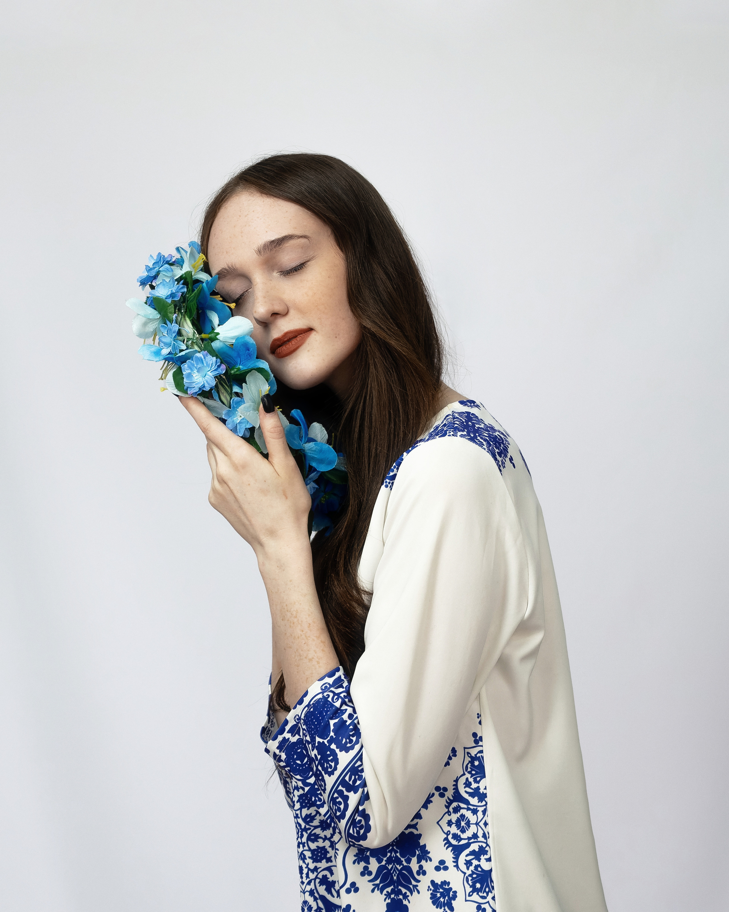 Девушка с веснушками с закрытыми глазами с венком в руках на белом фоне