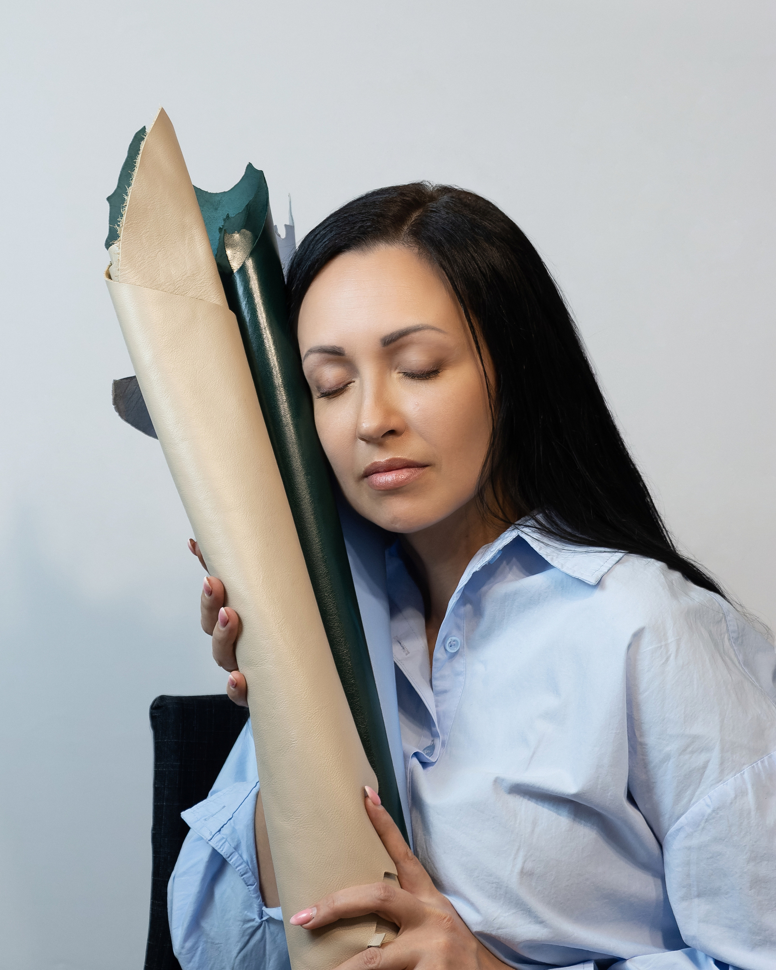 Фото девушки с закрытыми глазами с кожей в руках на белом фоне