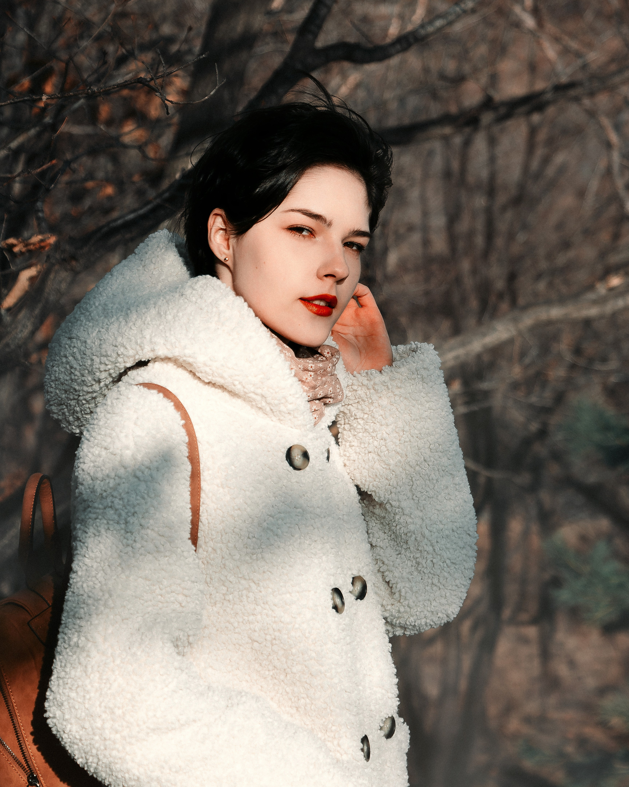 Девушка на улице около ёлок в солнечную погоду