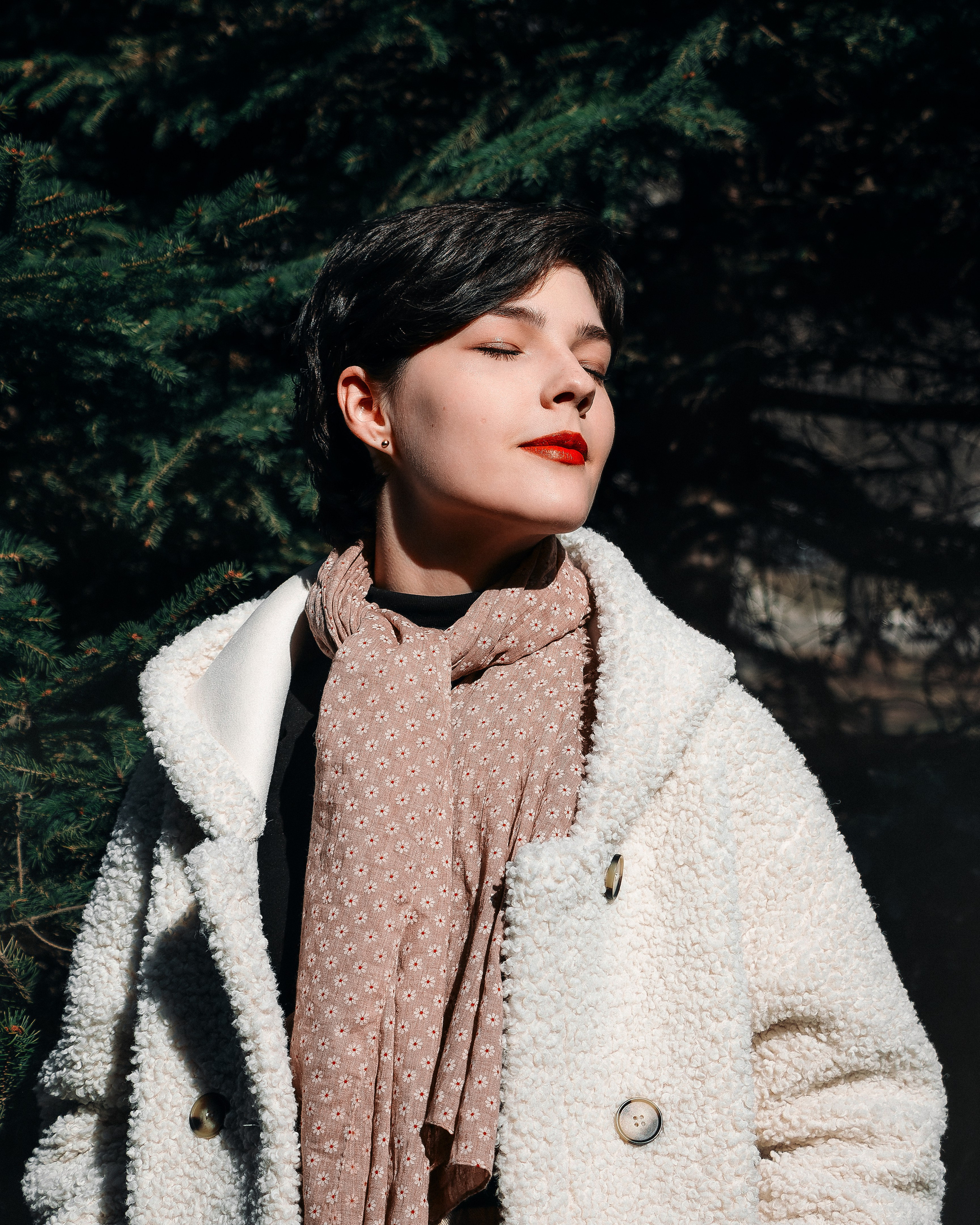 Девушка на улице около ёлок в солнечную погоду