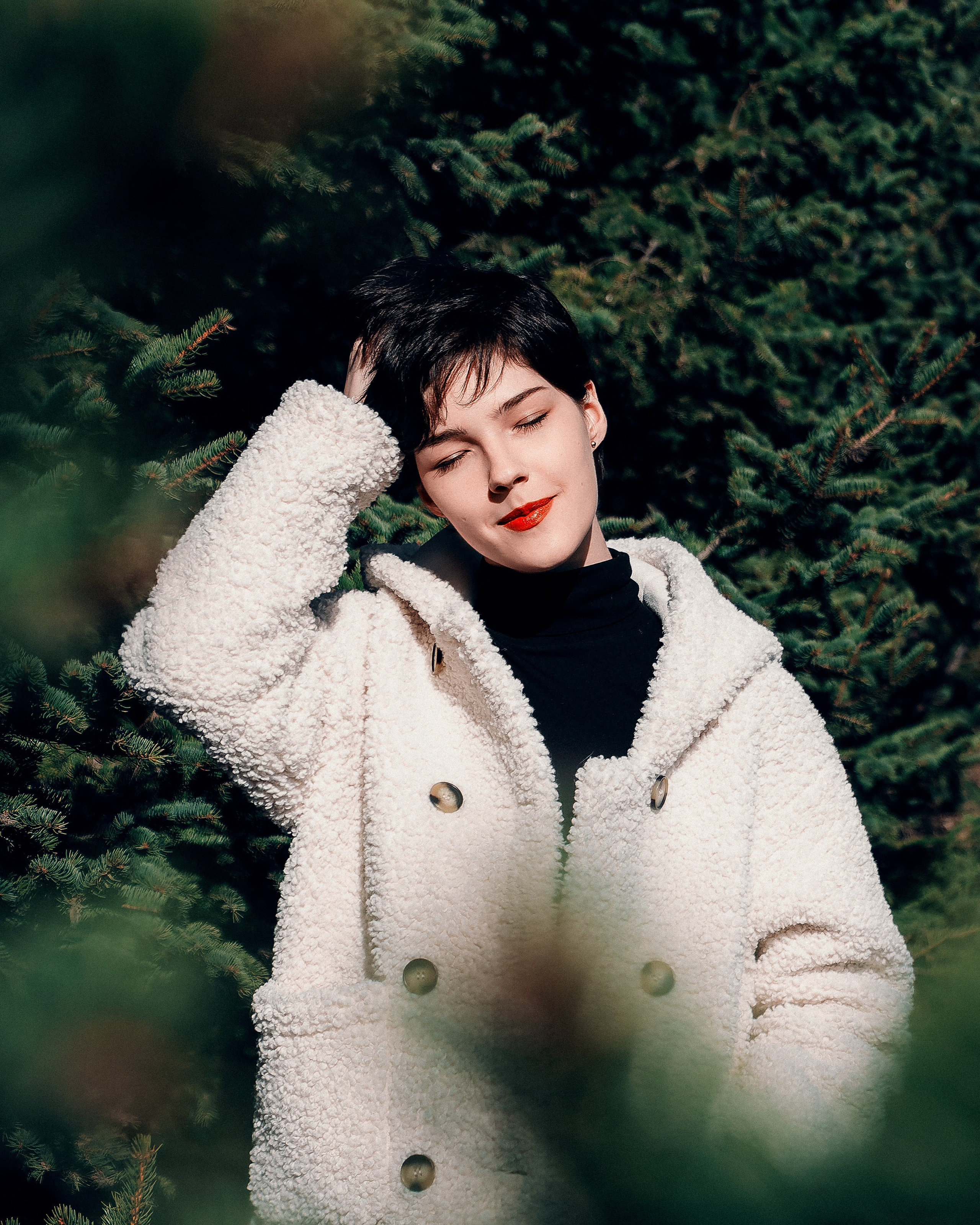 Девушка на улице около ёлок в солнечную погоду