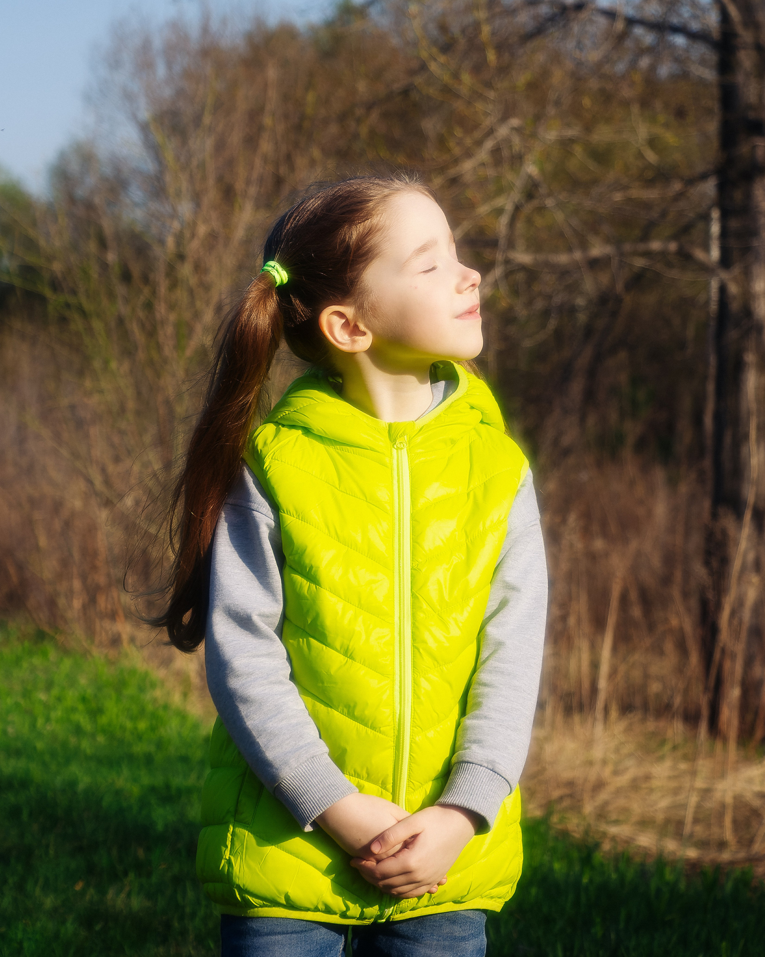 Девочка в зелёной жилетке на улице в солнечную погоду