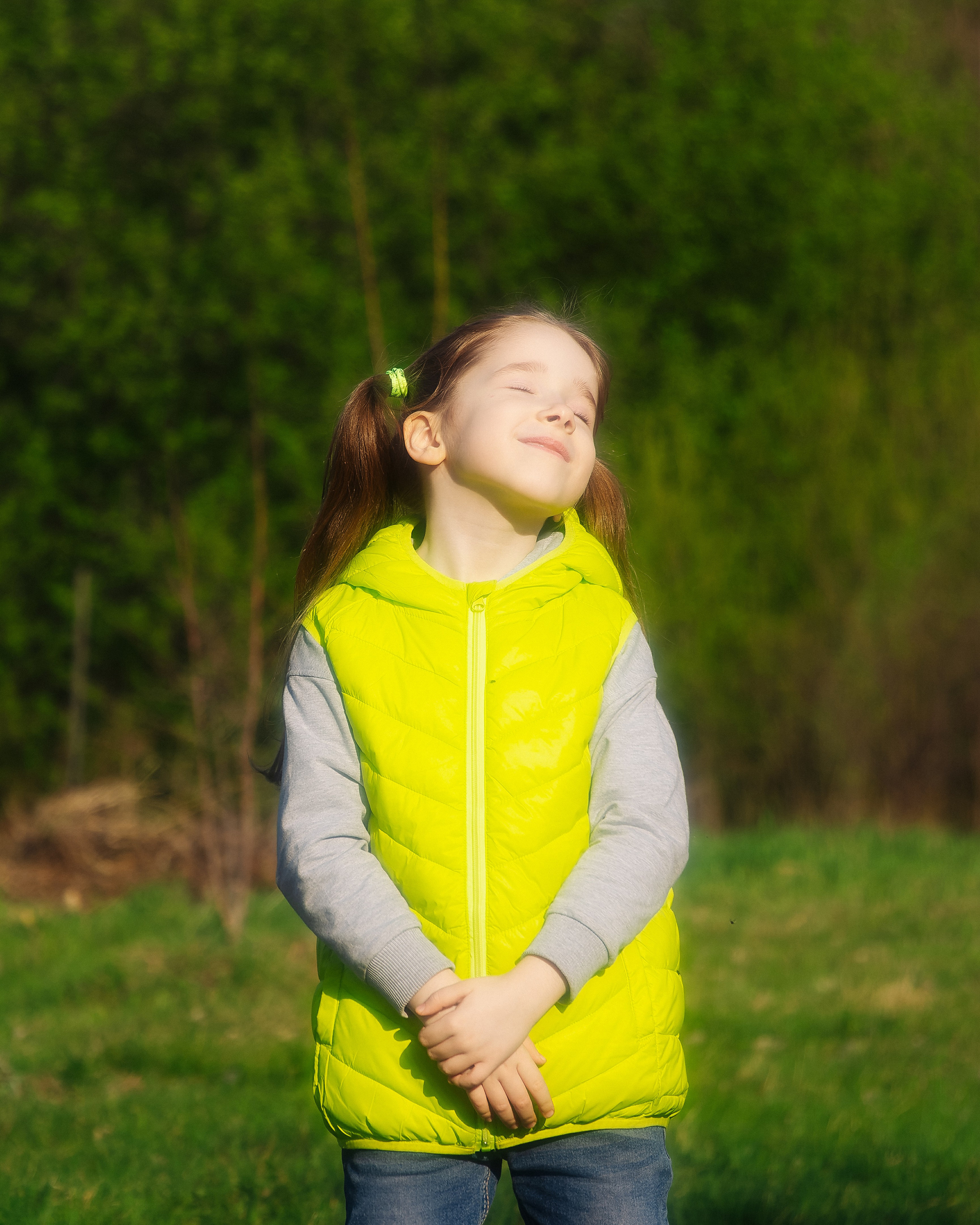 Девочка в зелёной жилетке на улице в солнечную погоду