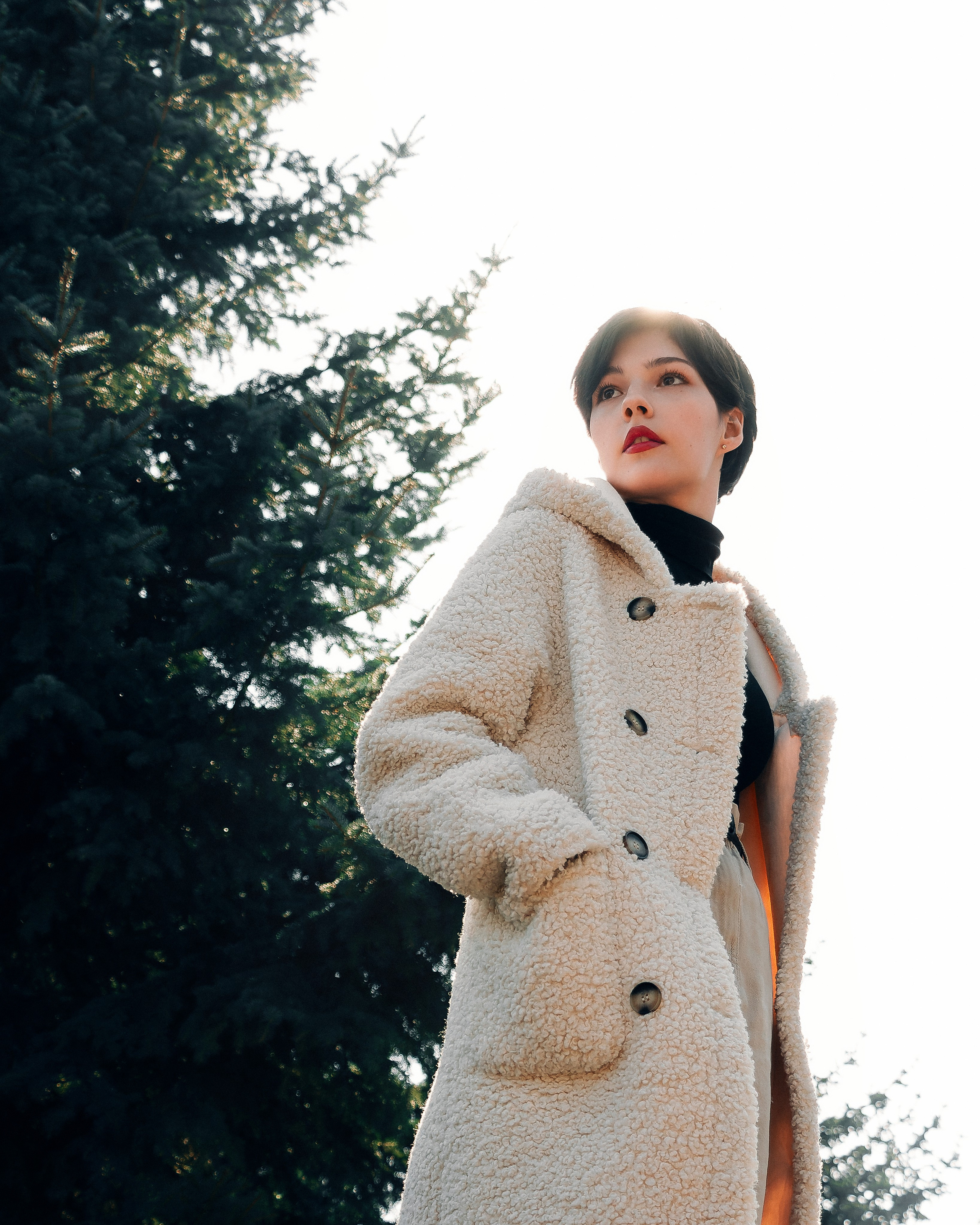 Девушка на улице около ёлок в солнечную погоду