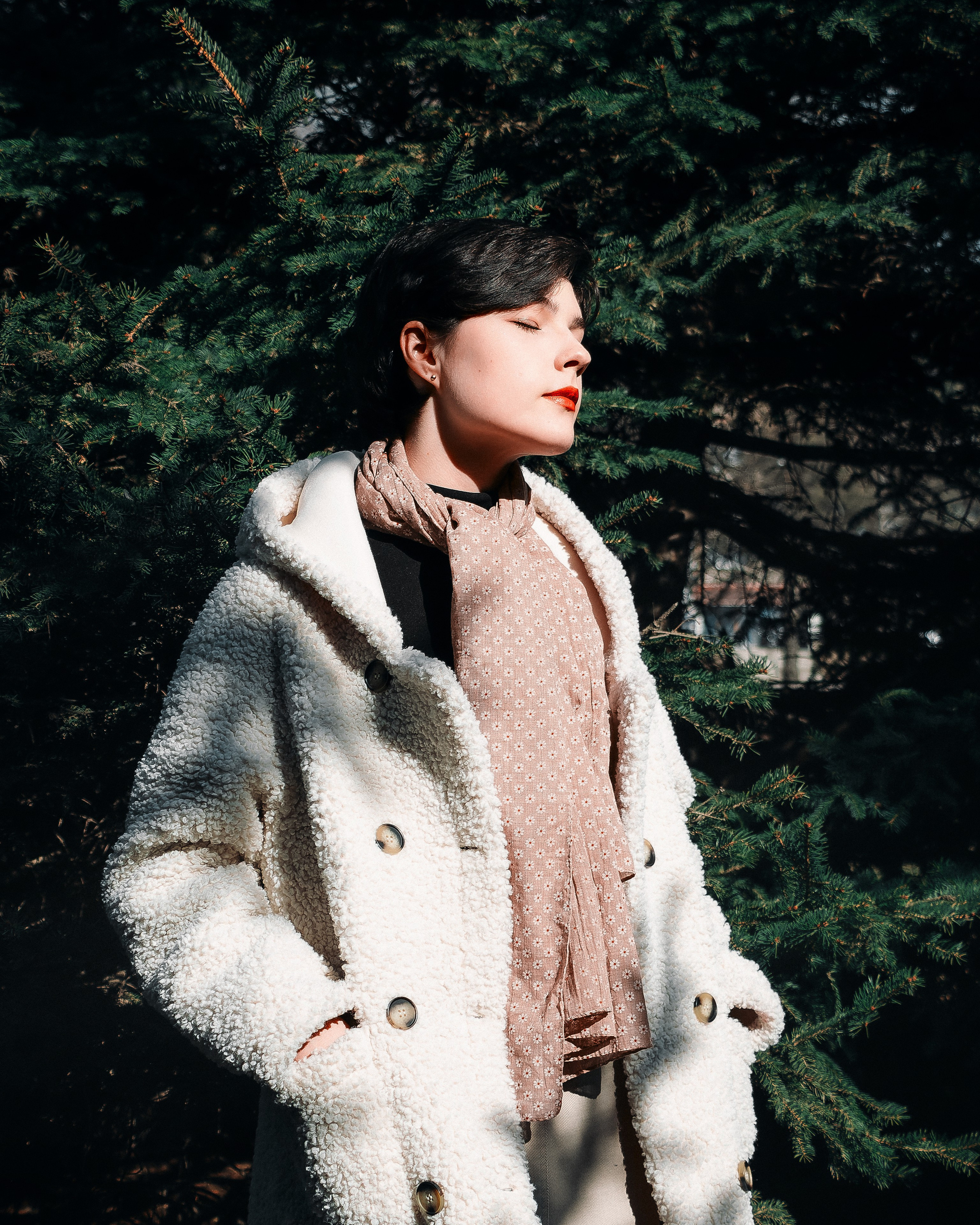 Девушка на улице около ёлок в солнечную погоду