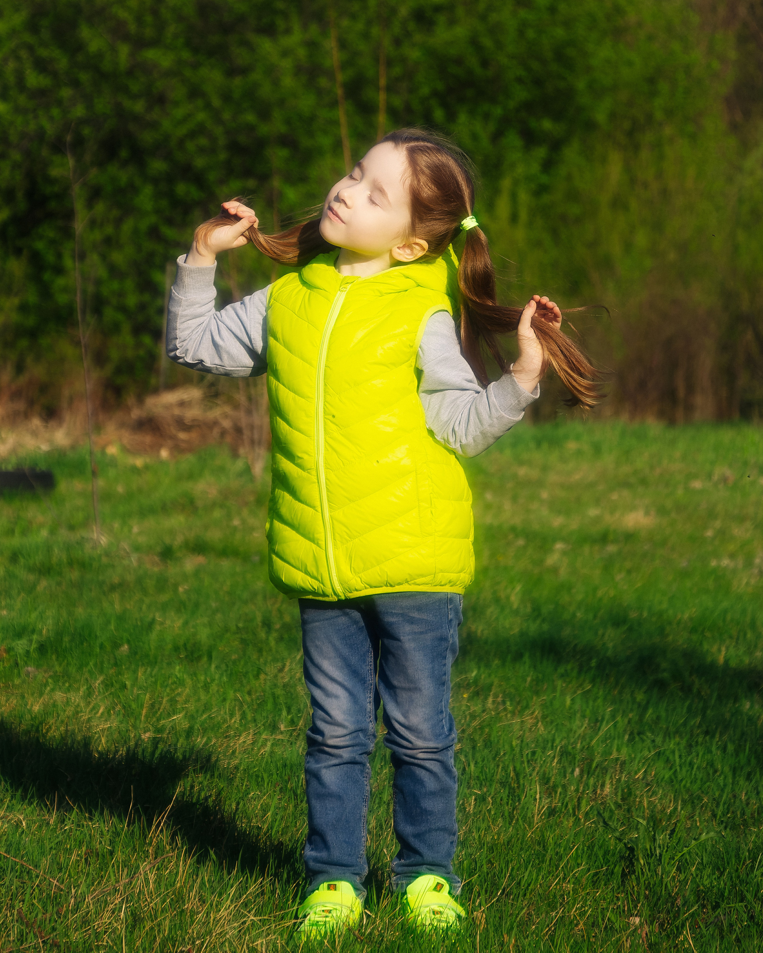 Девочка в зелёной жилетке на улице в солнечную погоду