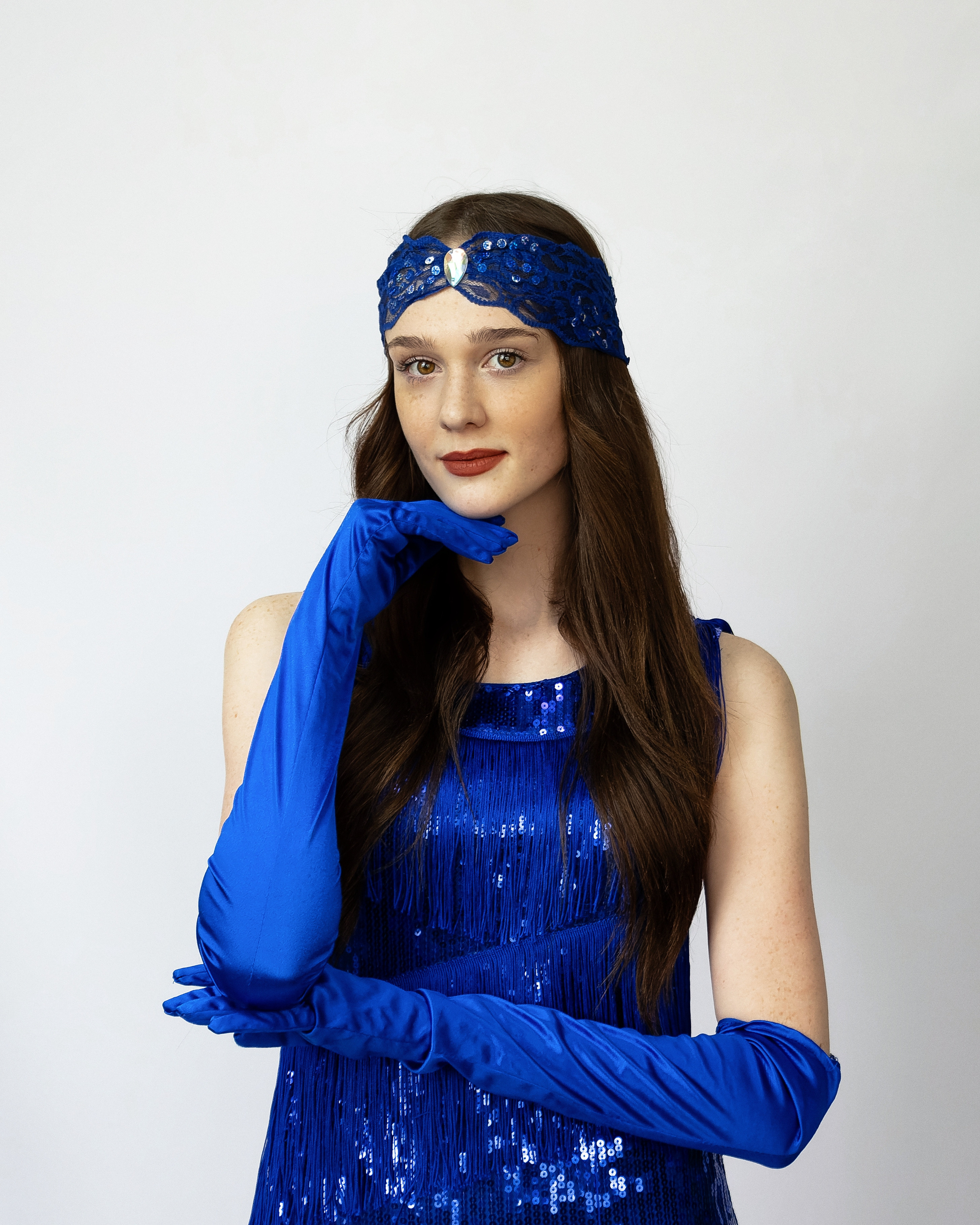 Девушка с веснушками в синем платье и перчатках на белом фоне