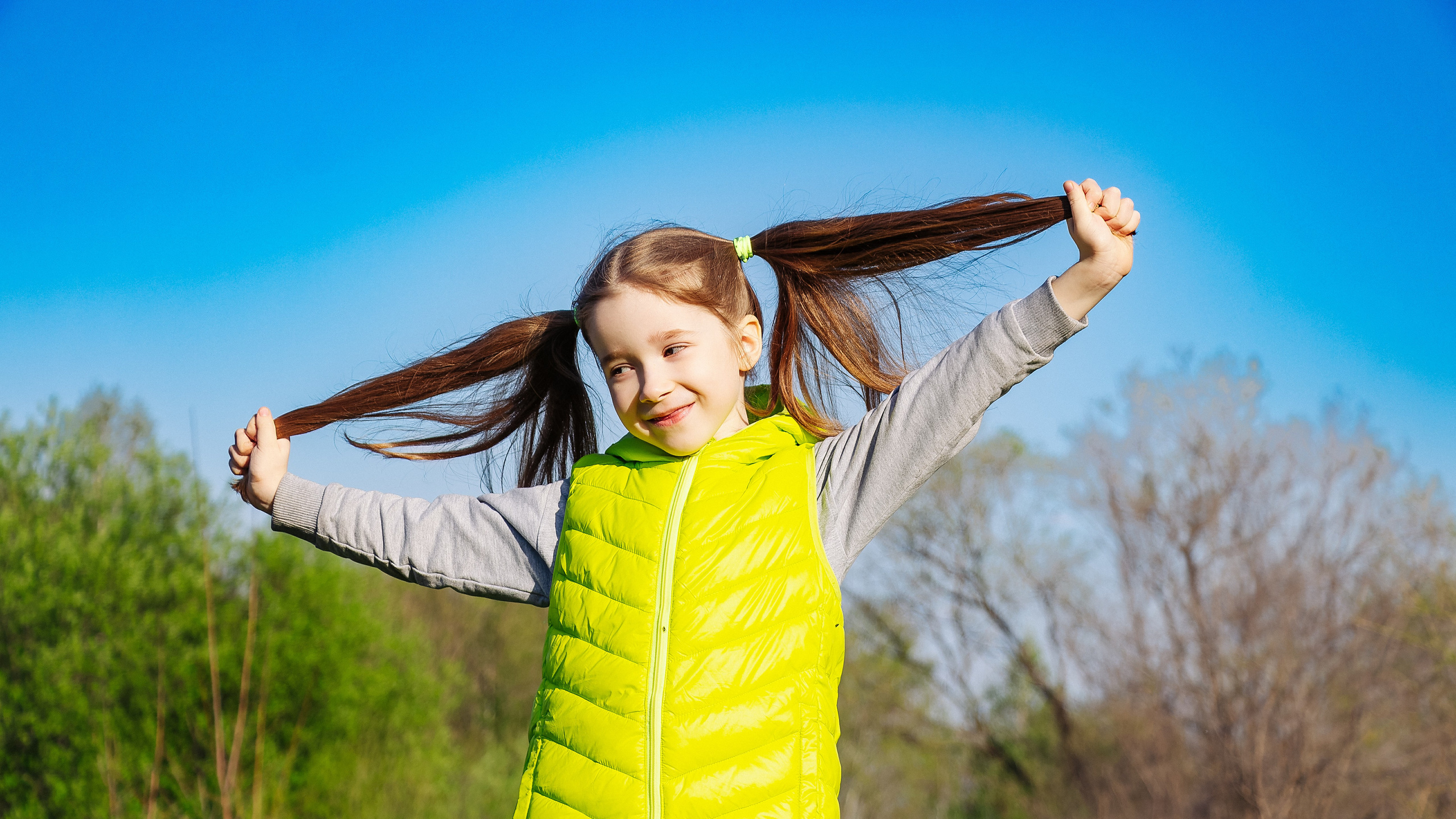 Девочка в зелёной жилетке на улице в солнечную погоду