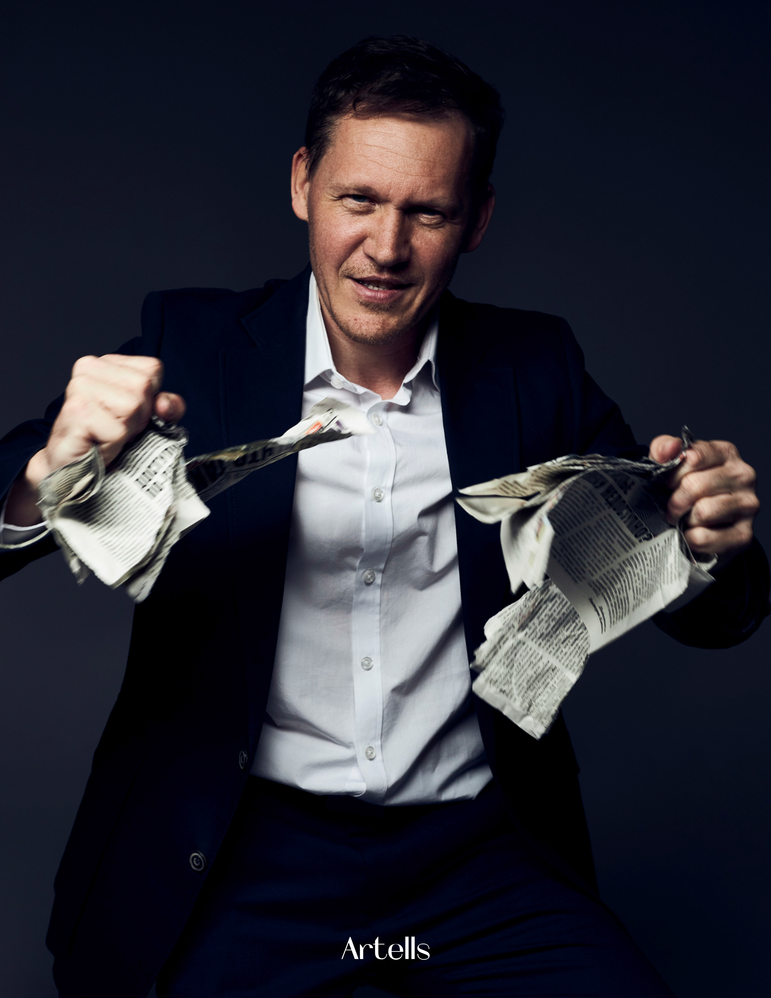 Портрет мужчины в деловом костюме, который рвёт газету на  куски и кидает их