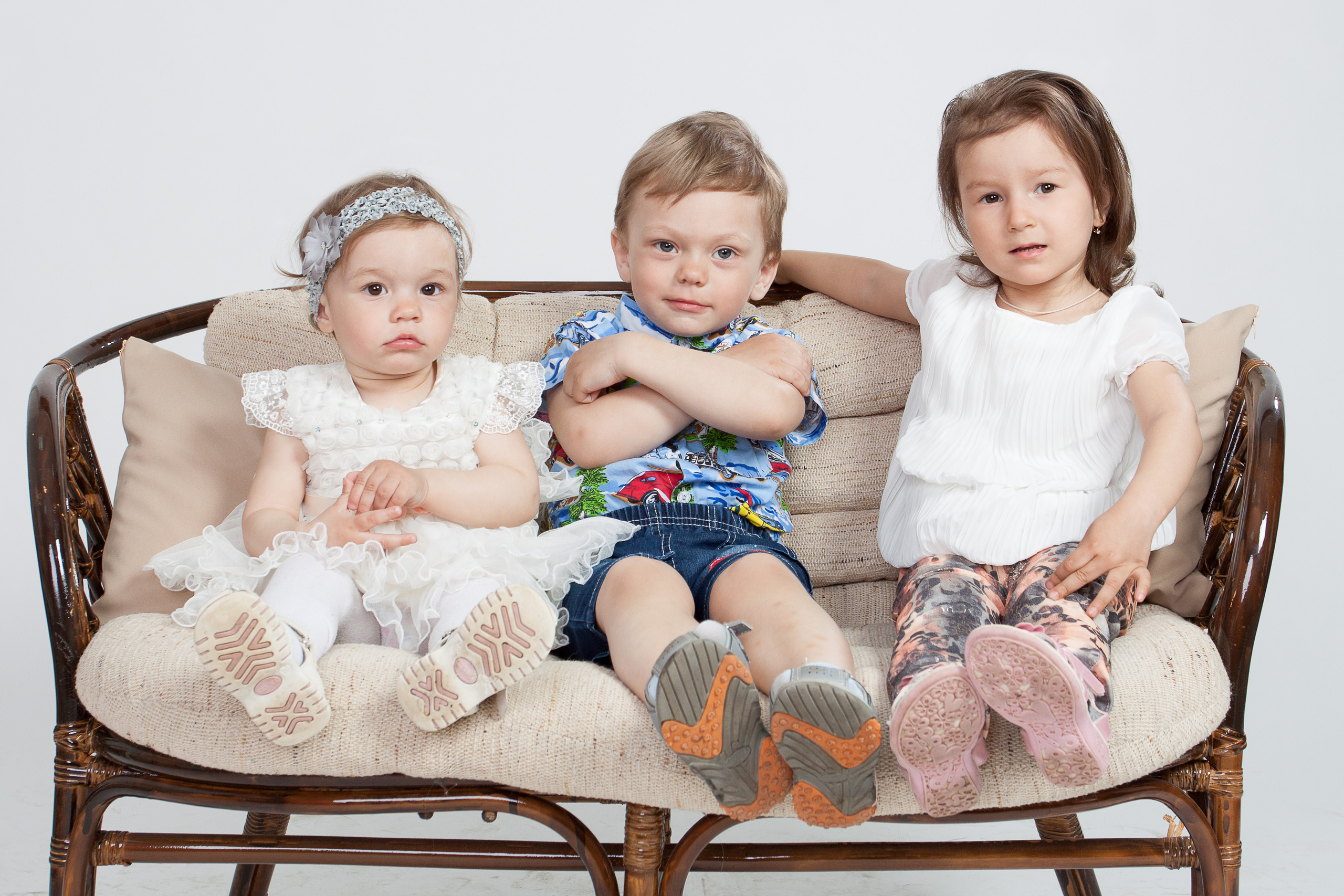 Три ребенка сидят на диване.