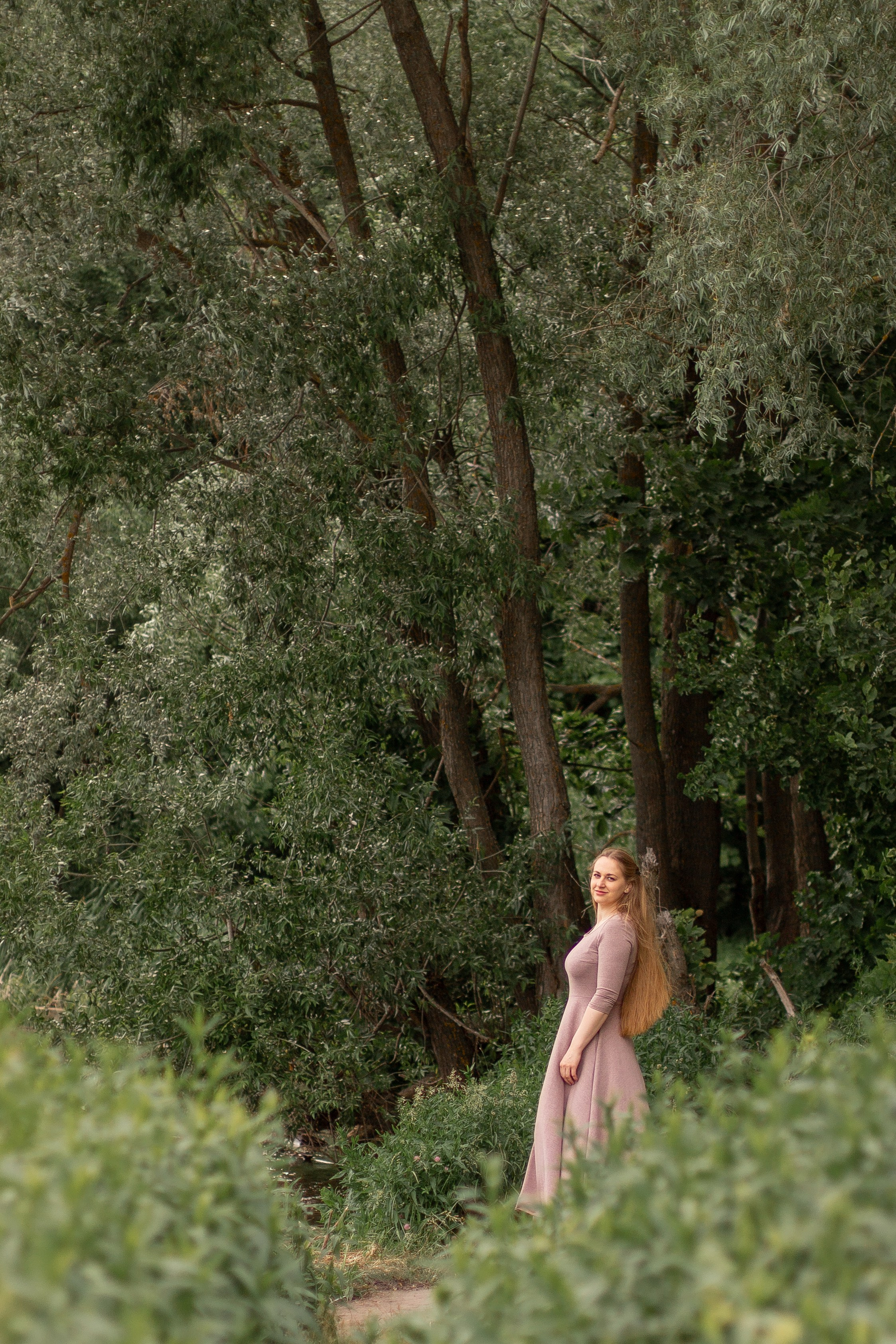 Фотосессия девушки летом, девушка с длинными волосами стоит на берегу реки