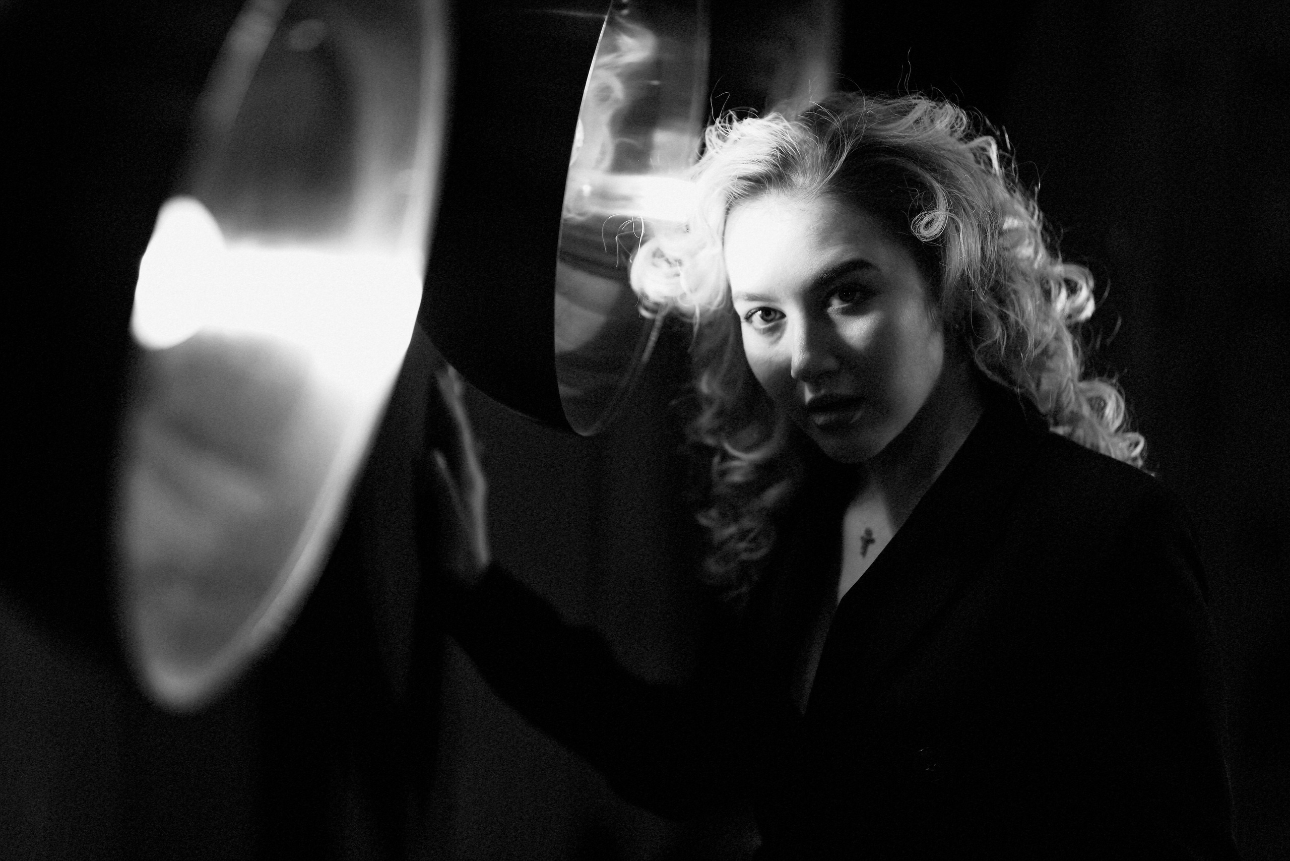 Художественный черно-белый портрет с эффектом дыма и контровым светом, кудрявые волосы, драматичное освещение, креативная съемка