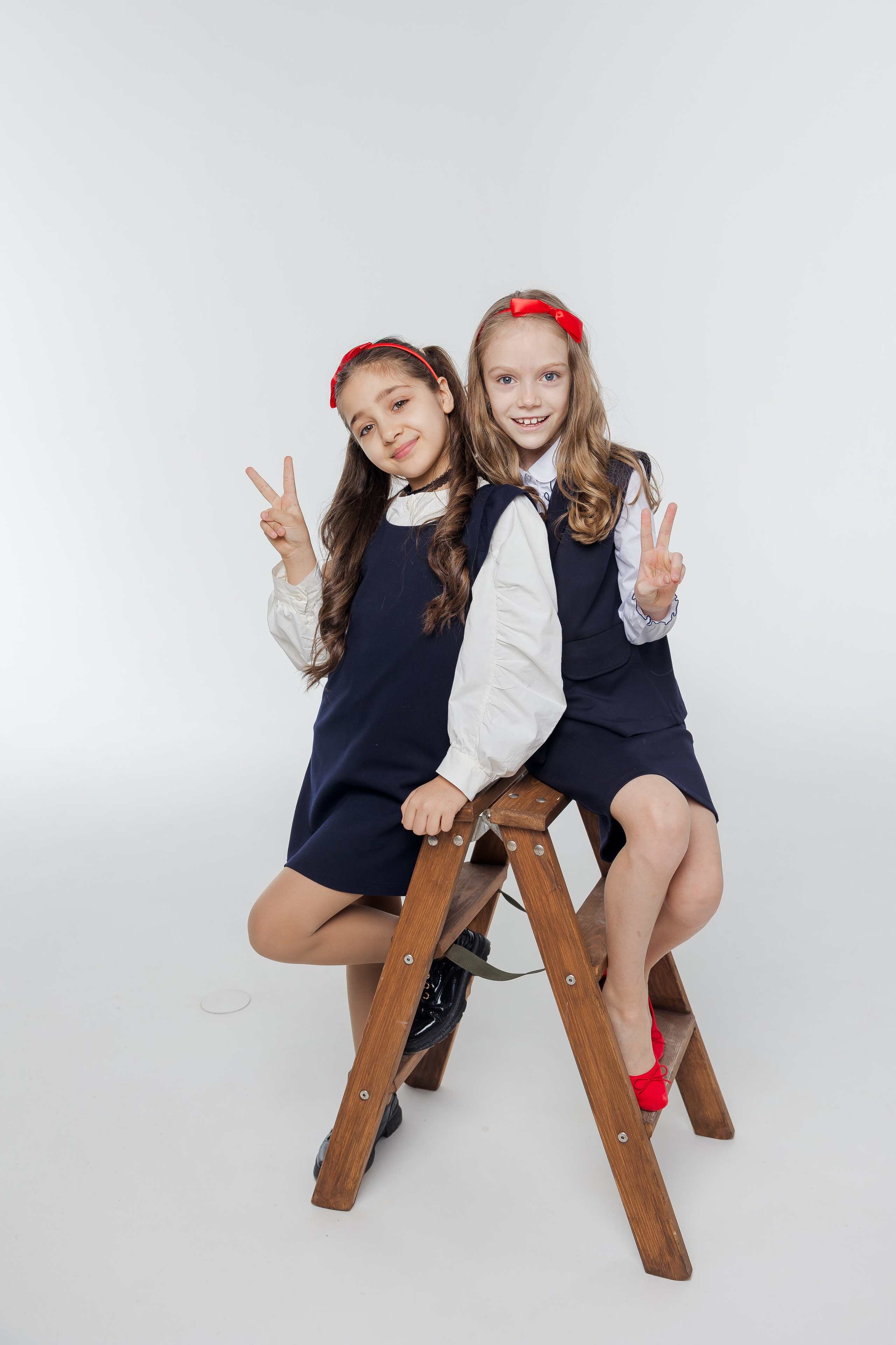 Две девочки стоят вместе в студии в одежде с красными акцентами