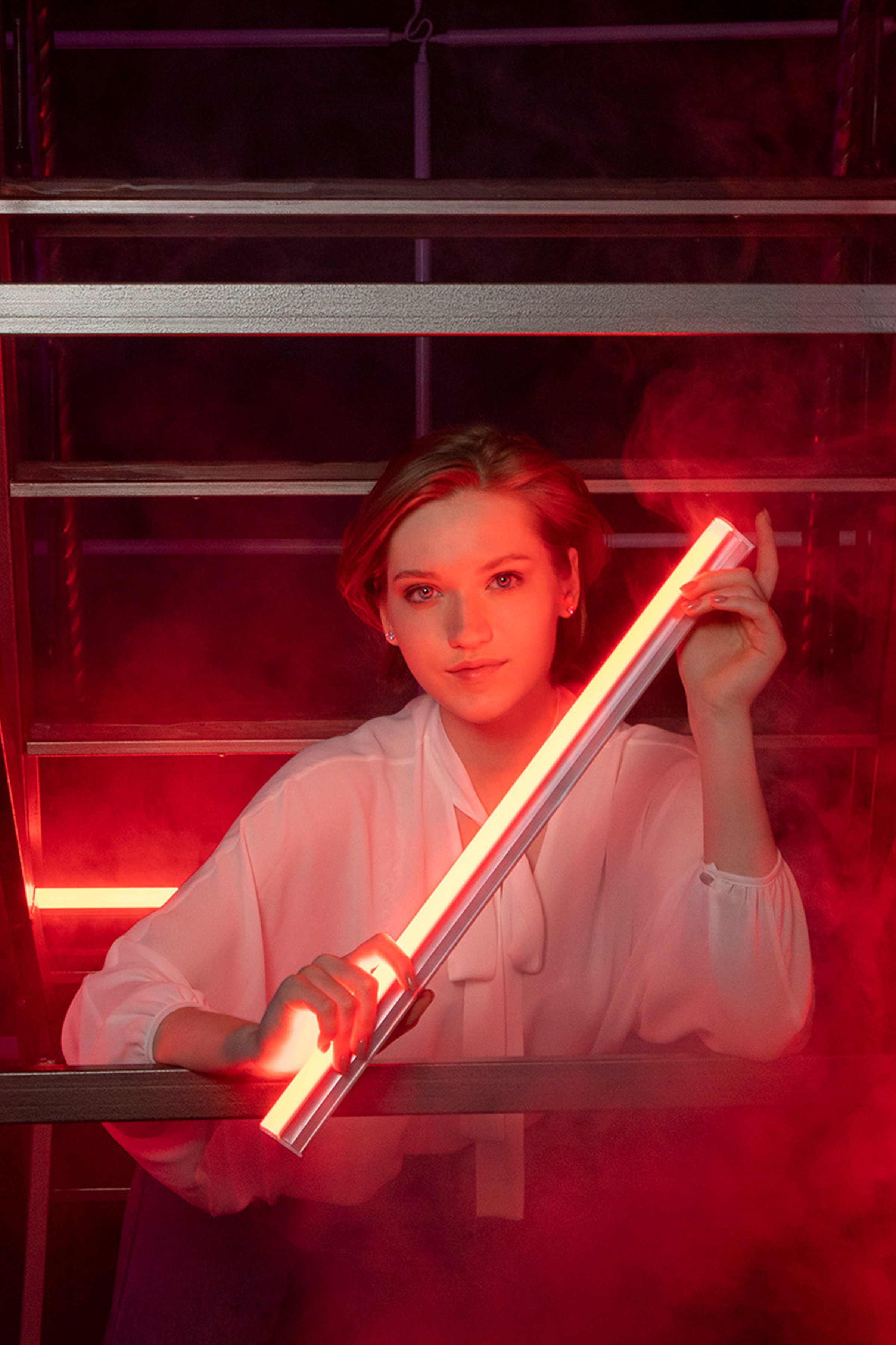 Женский портрет на тёмным фоне с красной лампой дымом студии