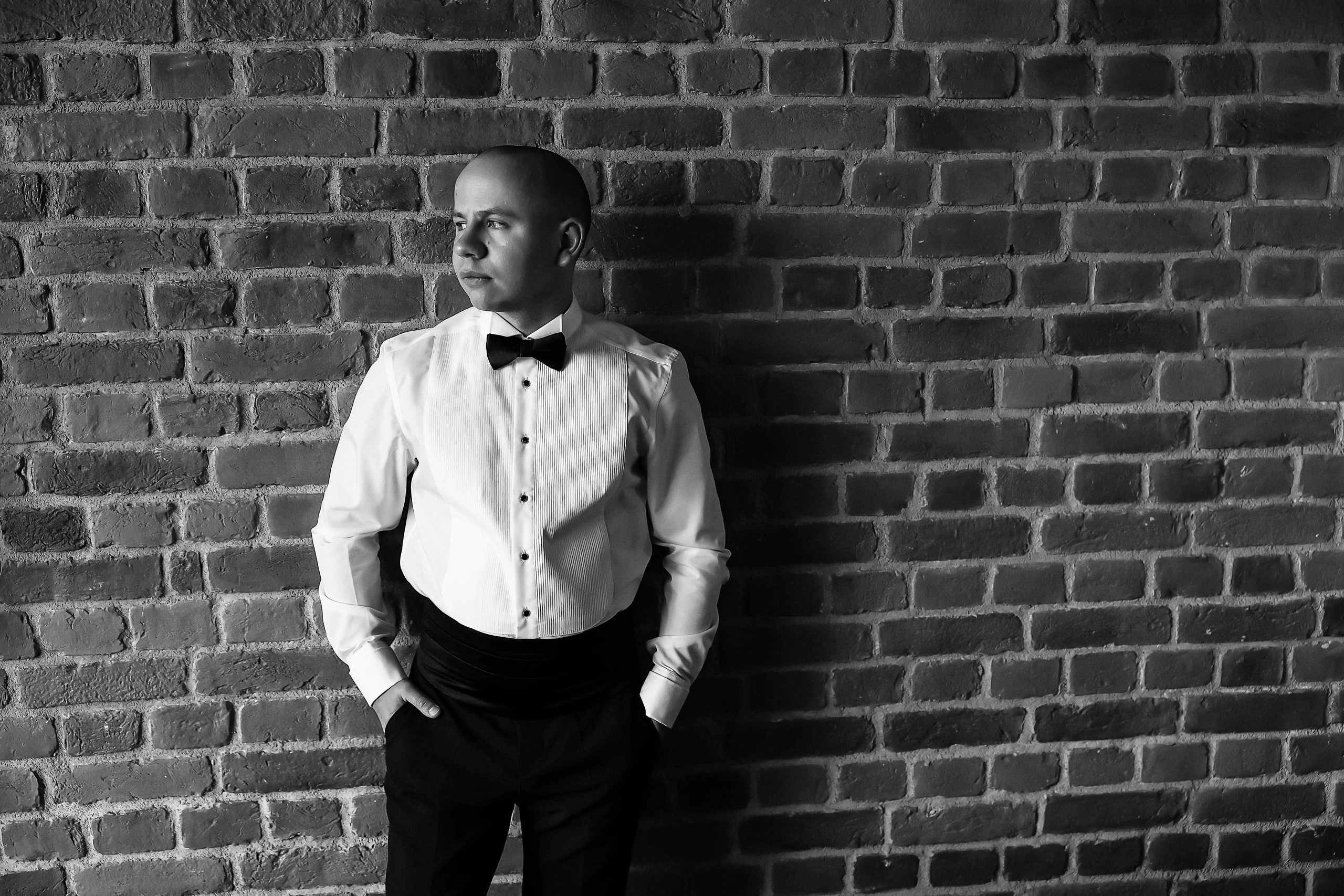 Портрет жениха в рубашке на фоне стены